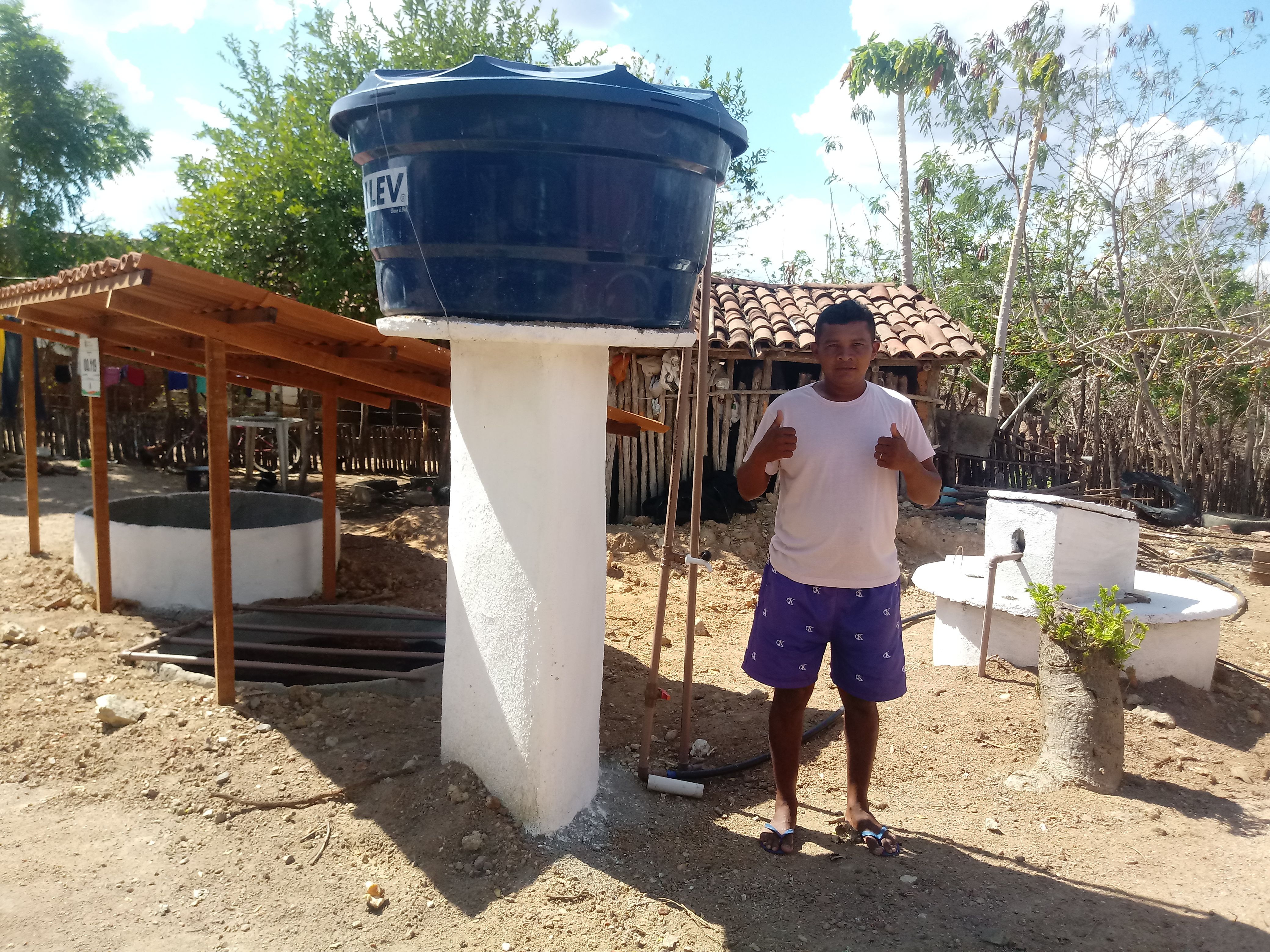 Agricultor ao lado do sistema de reúso de água cinza