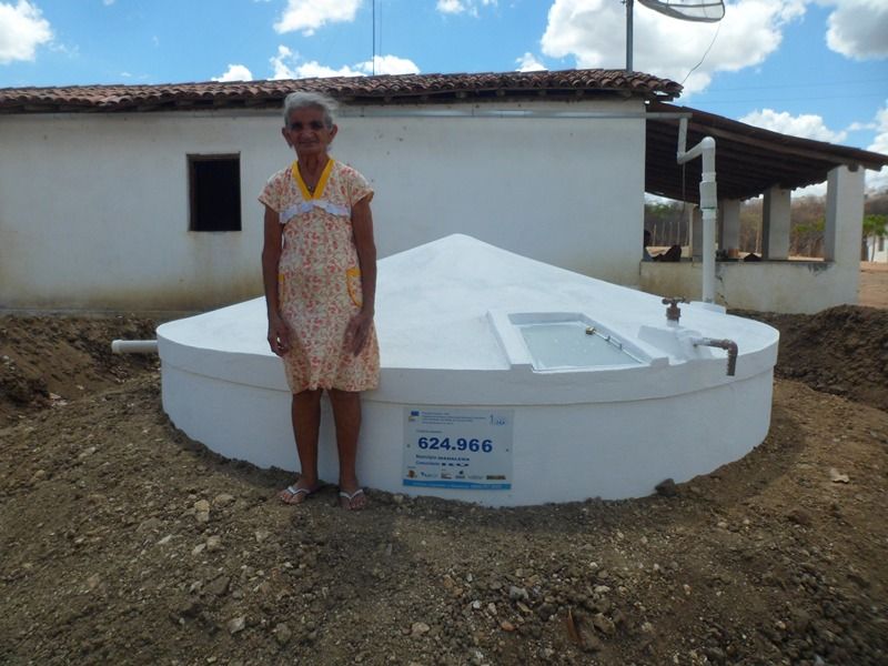 Agricultora ao lado de uma cisterna de placas recém-construída