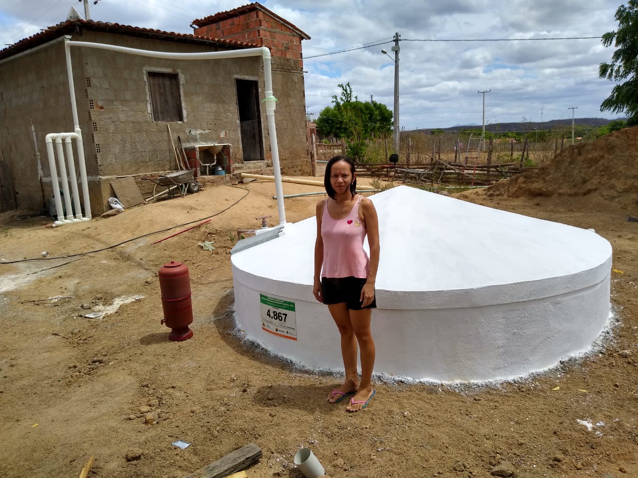 Agricultora ao lado de uma cisterna de placas de 16 mil litros