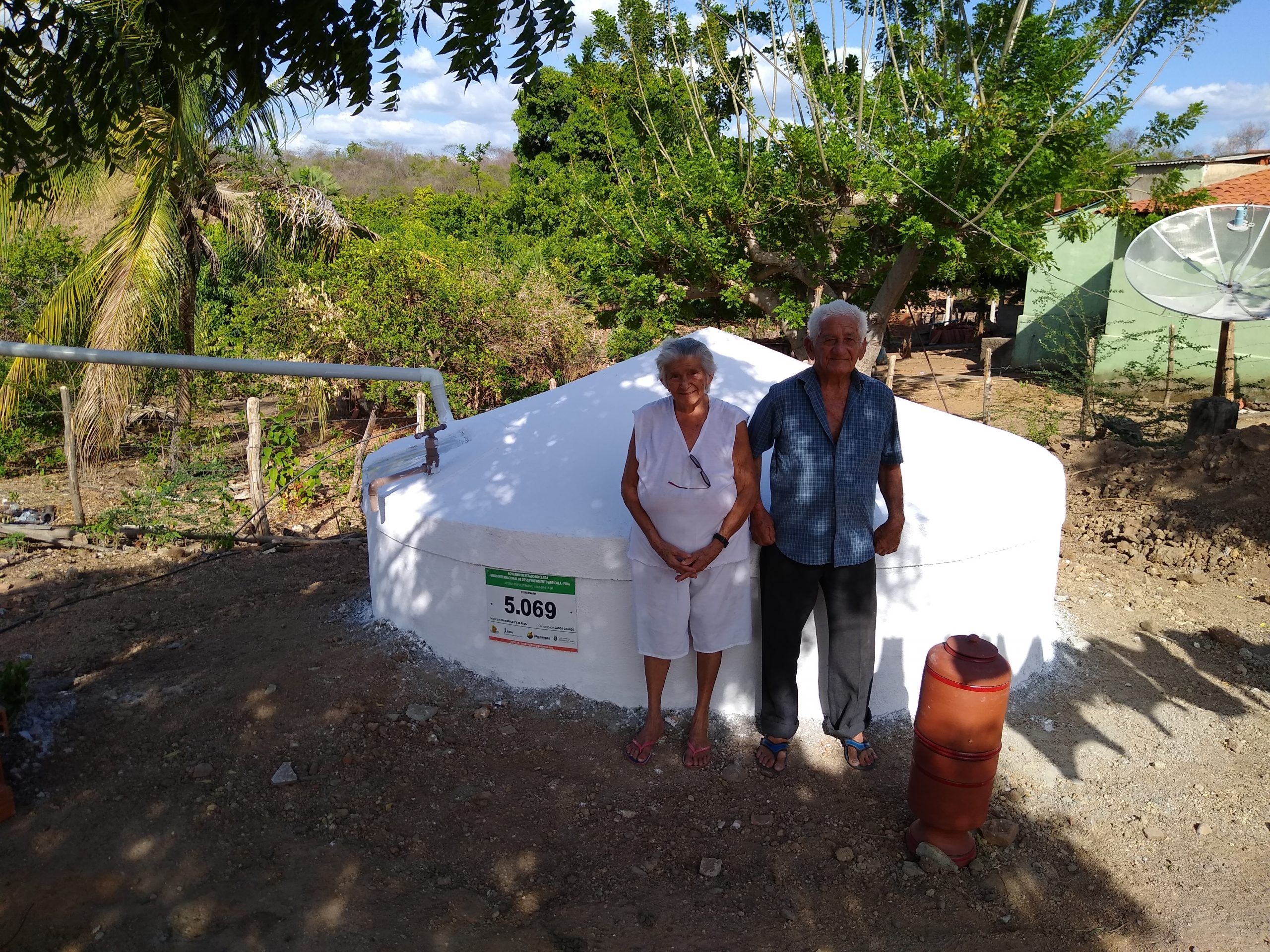 Casal de agricultores em frente à cisterna de placas recém-construída no terreiro de casa