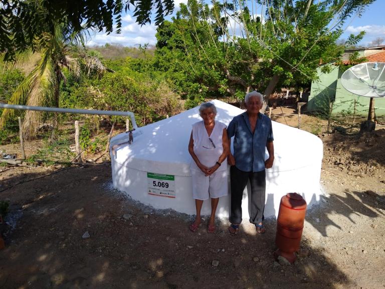 Casal de agricultores em frente à cisterna de placas recém-construída no terreiro de casa