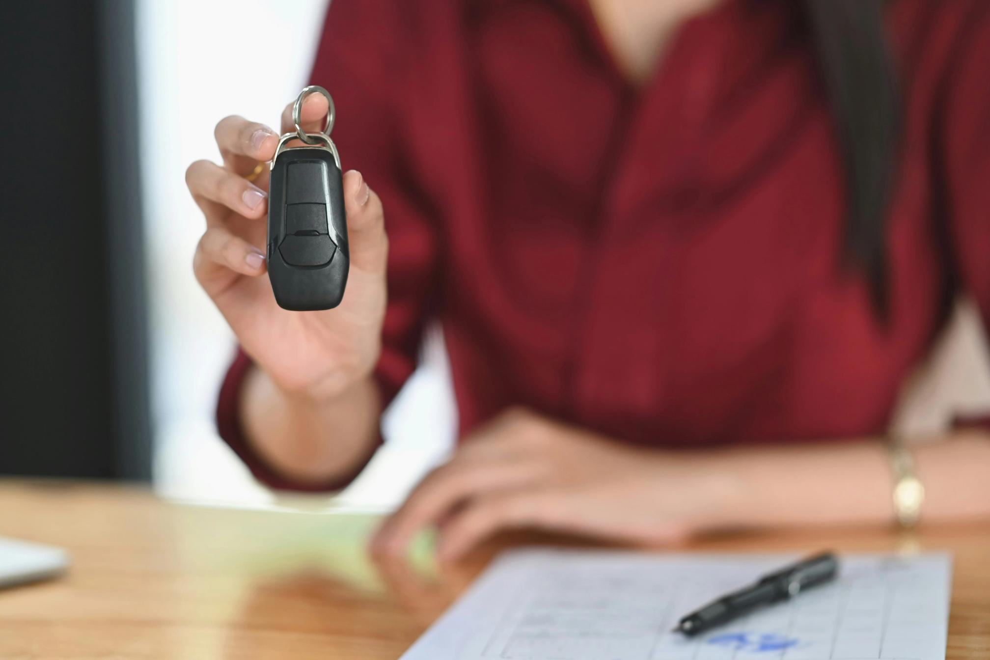 A woman holding car keys at a desk with paperwork