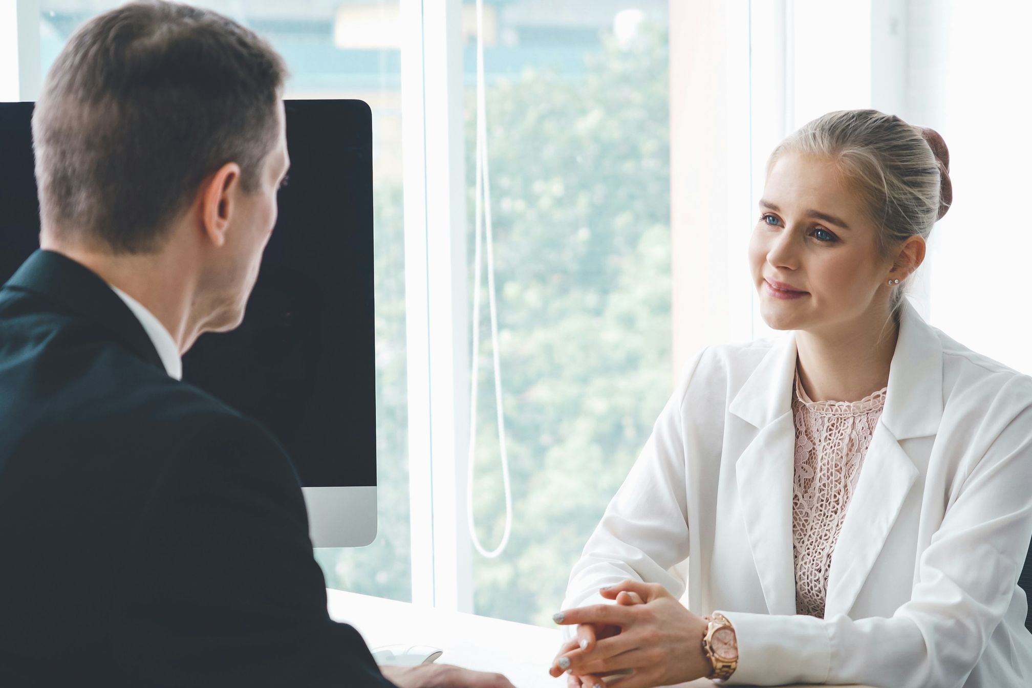 A young man in a suit being interviewed by a woman in a corporate office