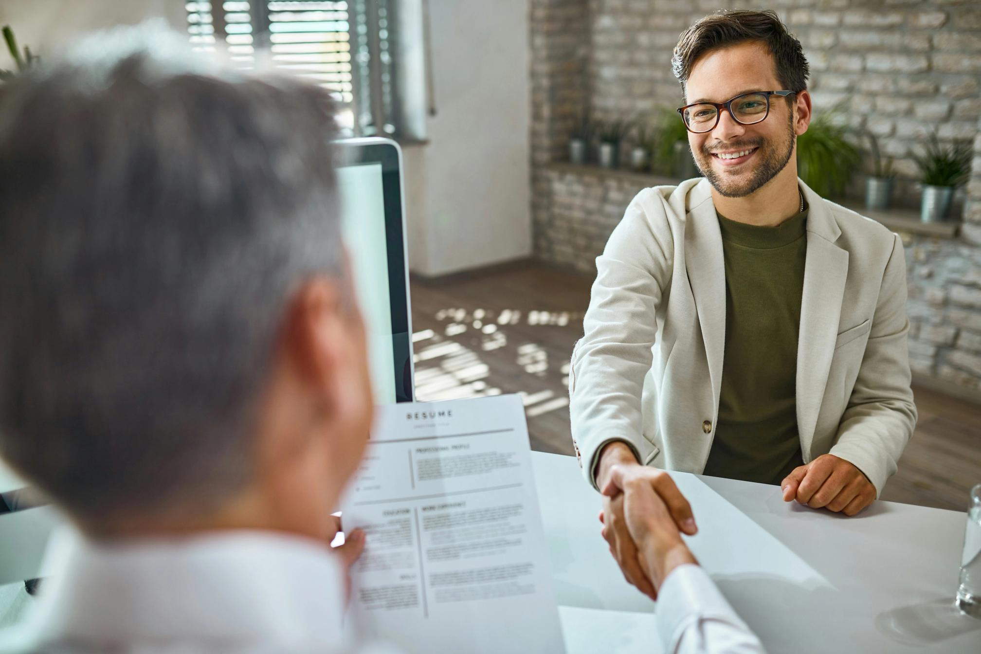 A man holding a resume interviewing another man