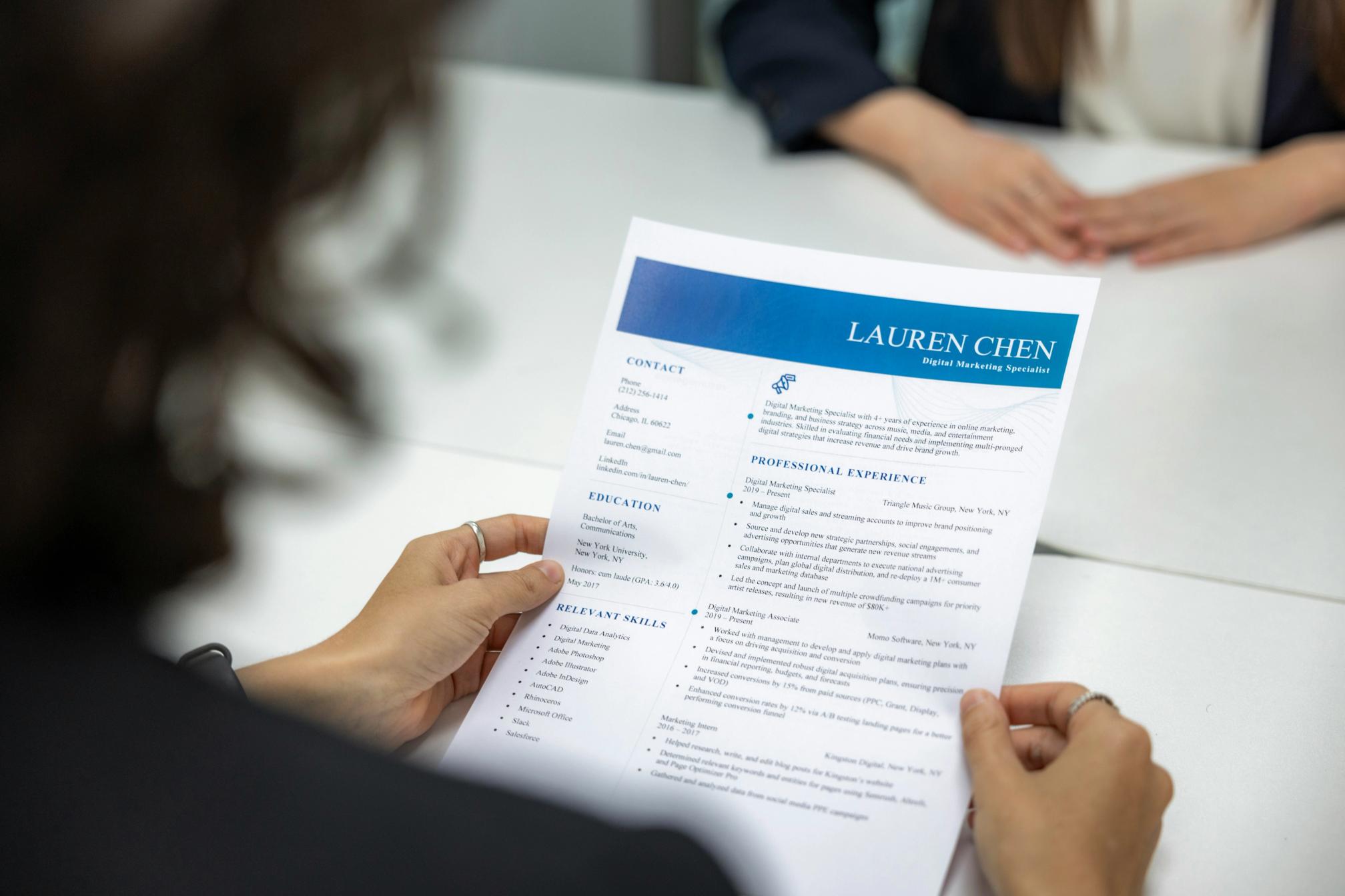 A woman holding a resume over a desk