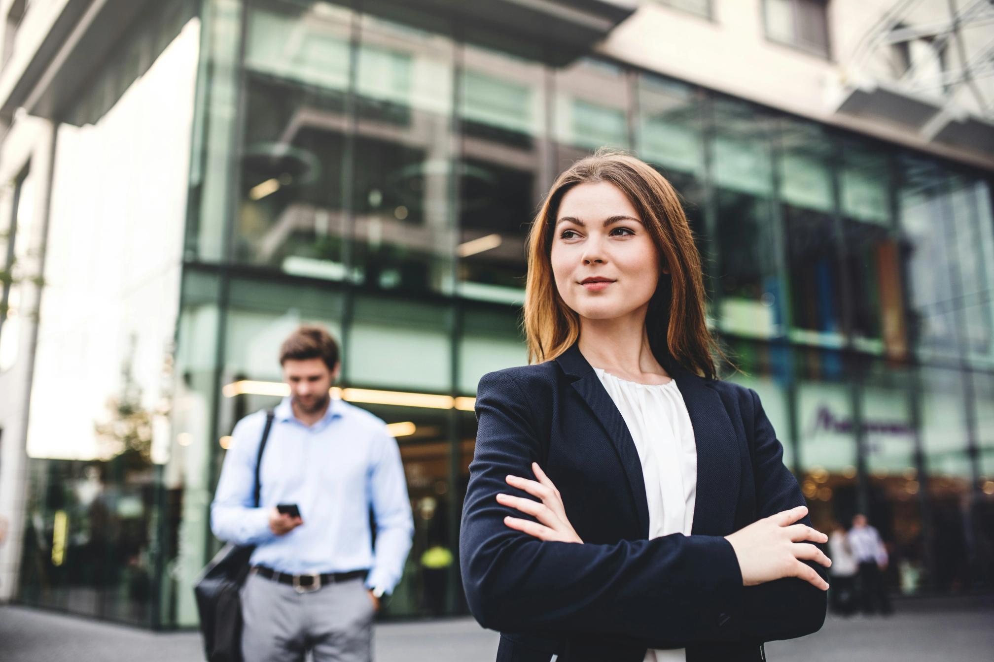 A woman wearing a suit with her arms folded outside of an office