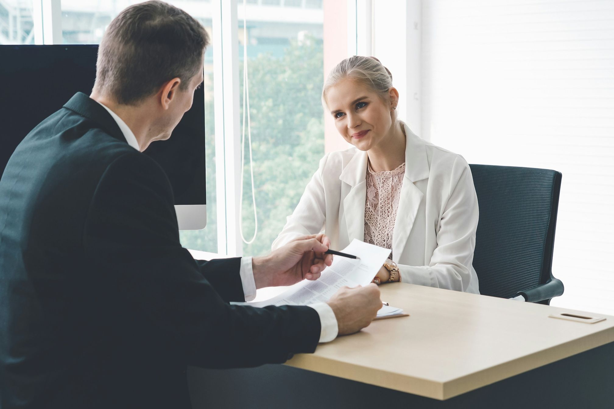 A man interviewing a woman in a corporate setting