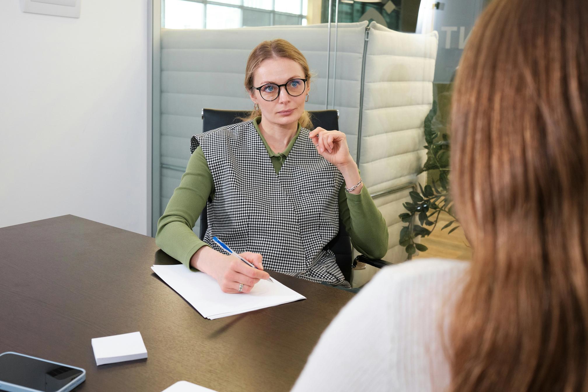 A blonde woman with glasses conducting a job interview