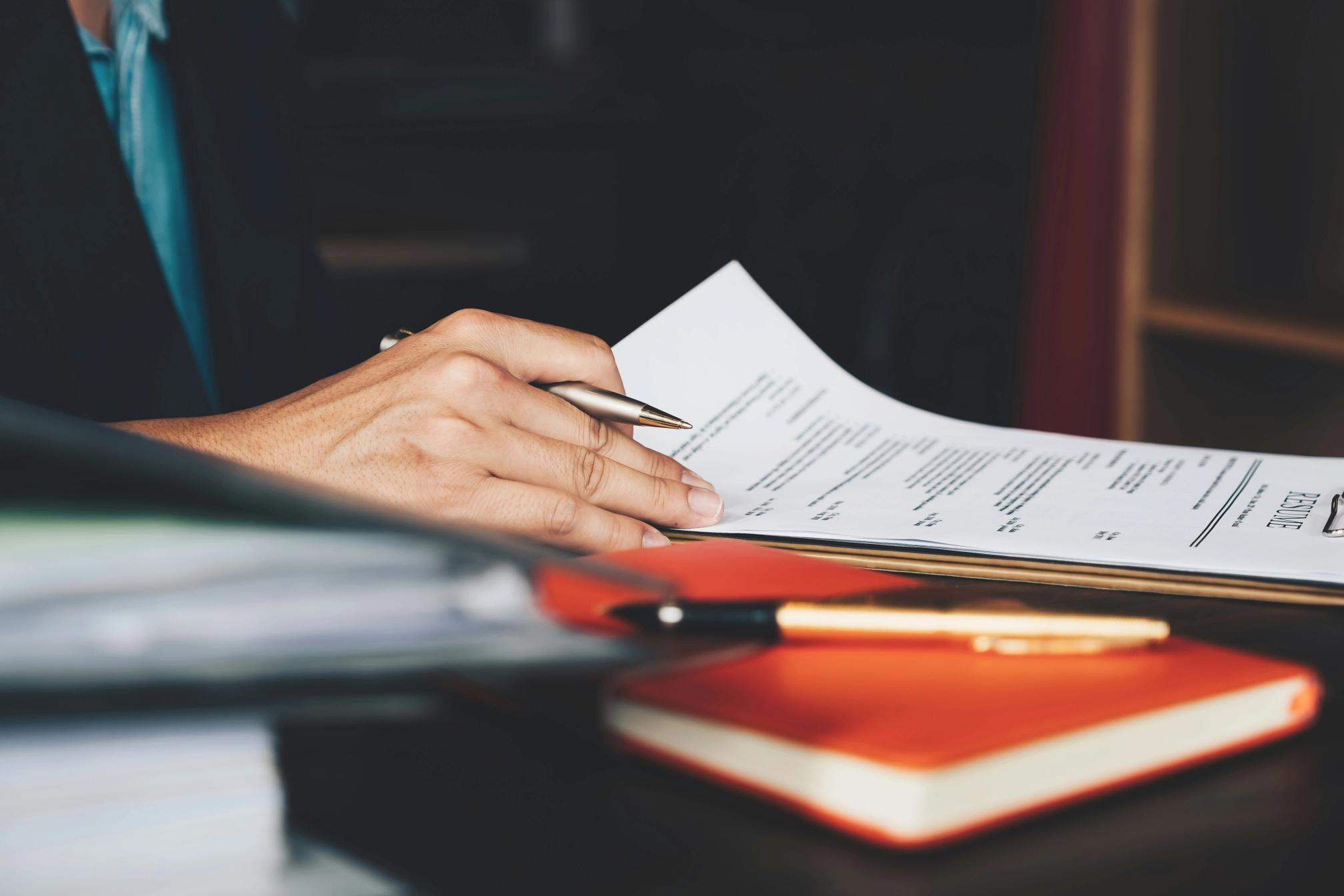 A hand on a resume on a desk