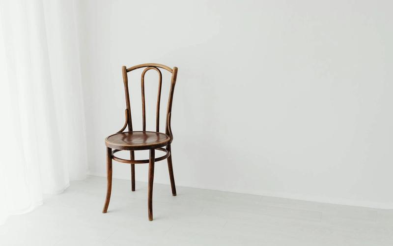 A solitary wooden chair in a bright minimalist interior.