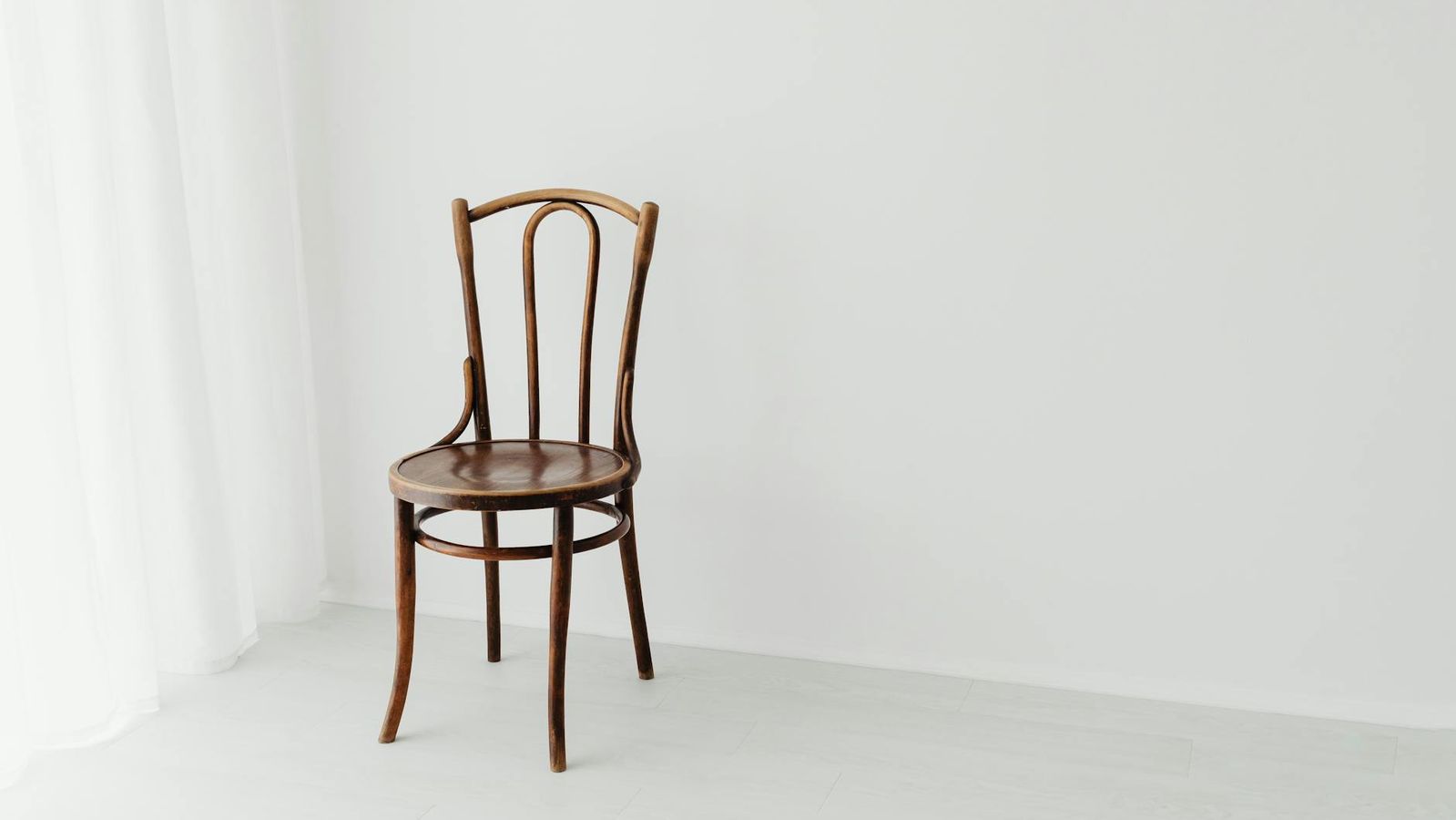 A solitary wooden chair in a bright minimalist interior.