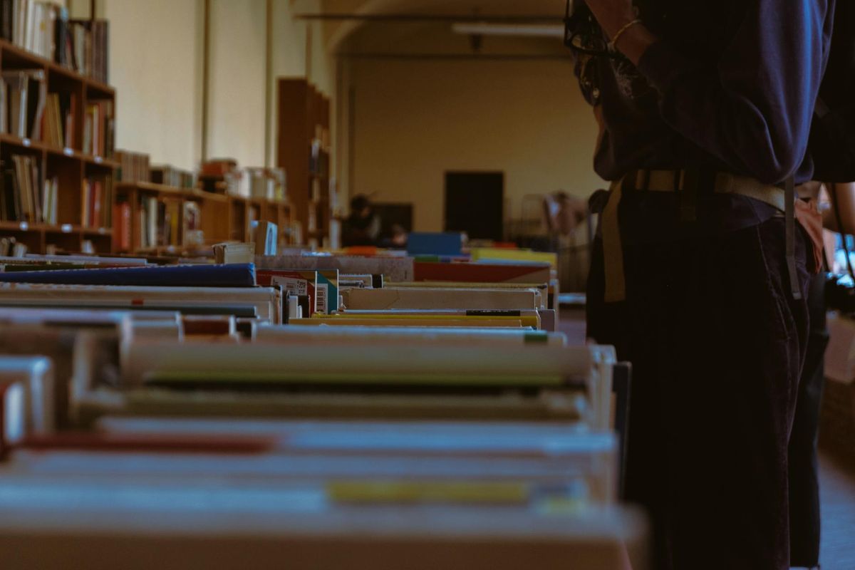 A quiet library with rows of books on long wooden shelves.