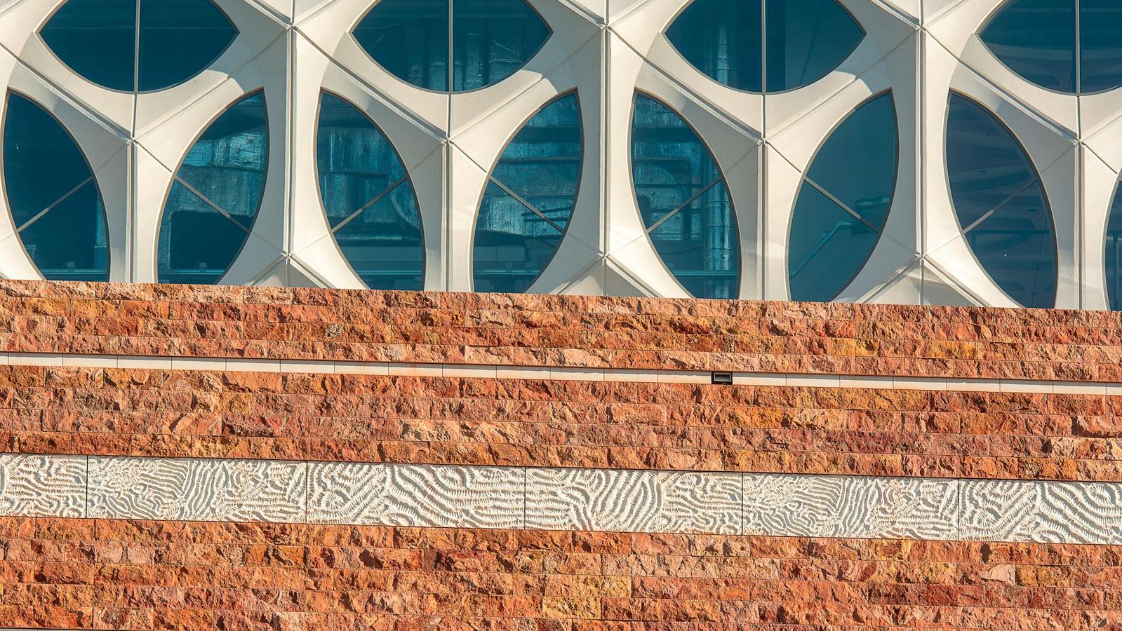 En moderne arkitektonisk facade med geometriske mønstre i mursten og glas.
