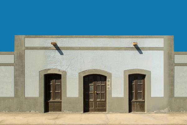 A symmetrical facade with three wooden doors under a clear blue sky.
