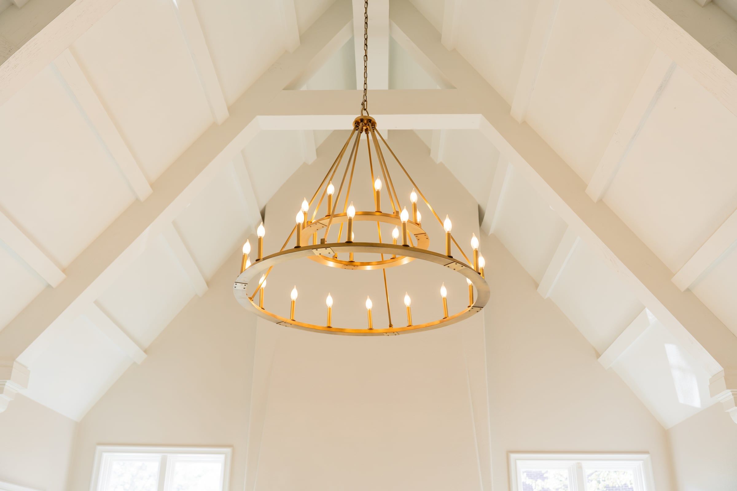 Vaulted ceiling with exposed beams and a two-tier ring chandelier