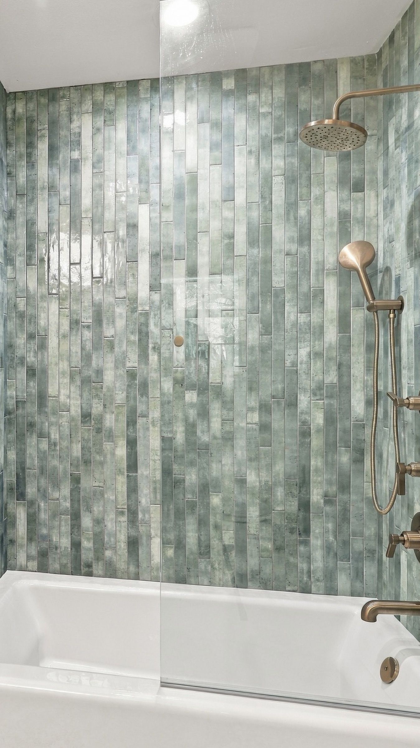 Jack-and-Jill bath after: the tub with green glass tile to the ceiling and a glass panel