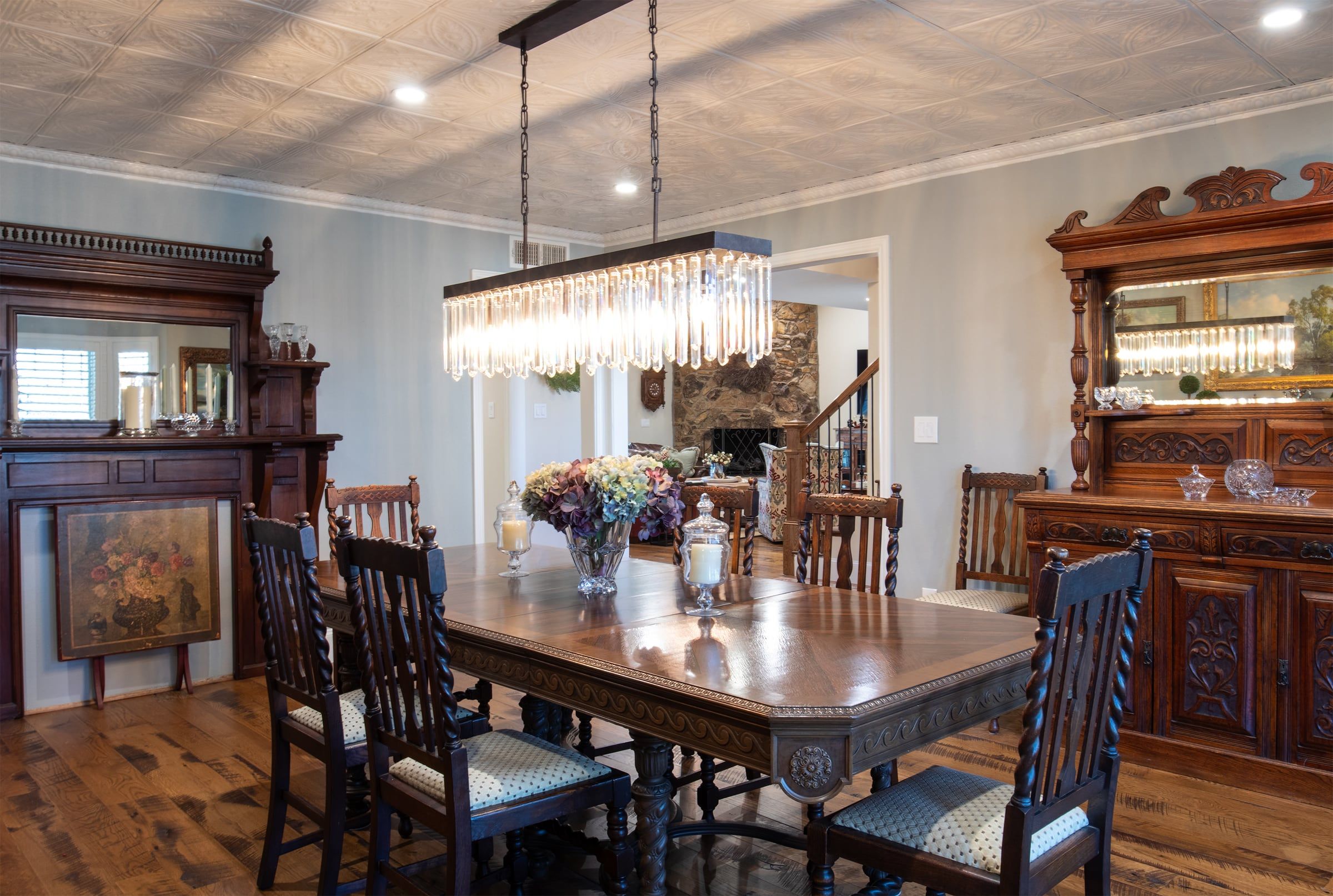 Dining room with a crystal chandelier over a carved wood table and antique sideboards