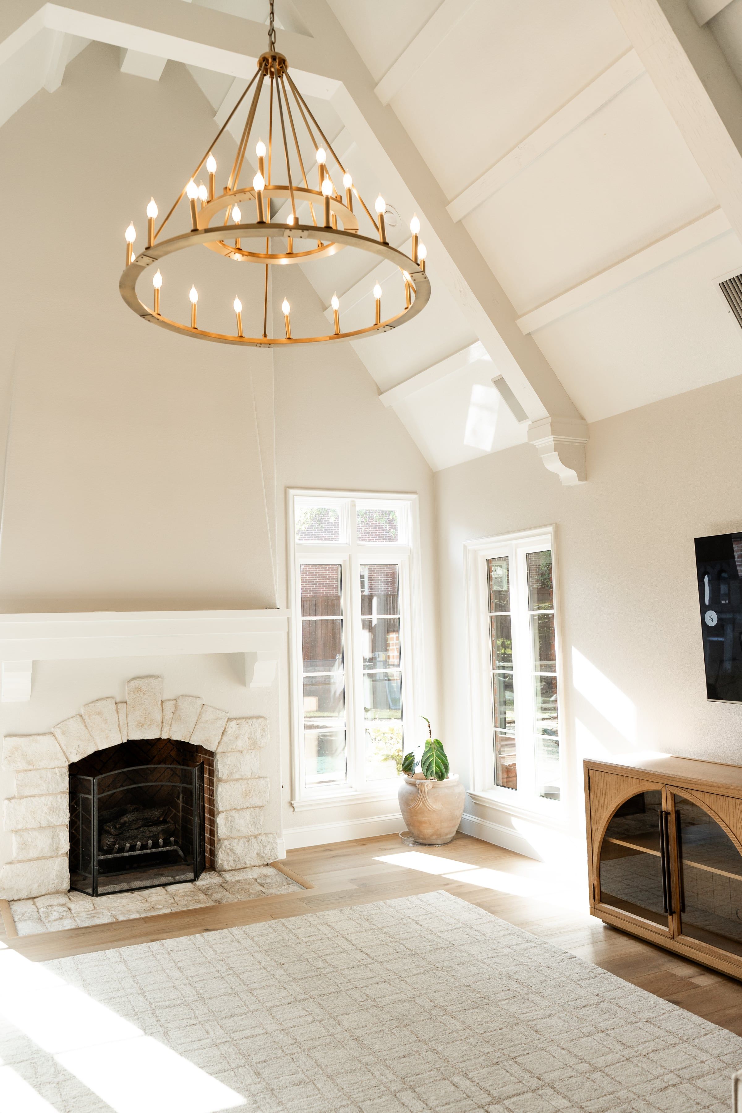 Living room under a vaulted ceiling with a fireplace and a two-tier chandelier