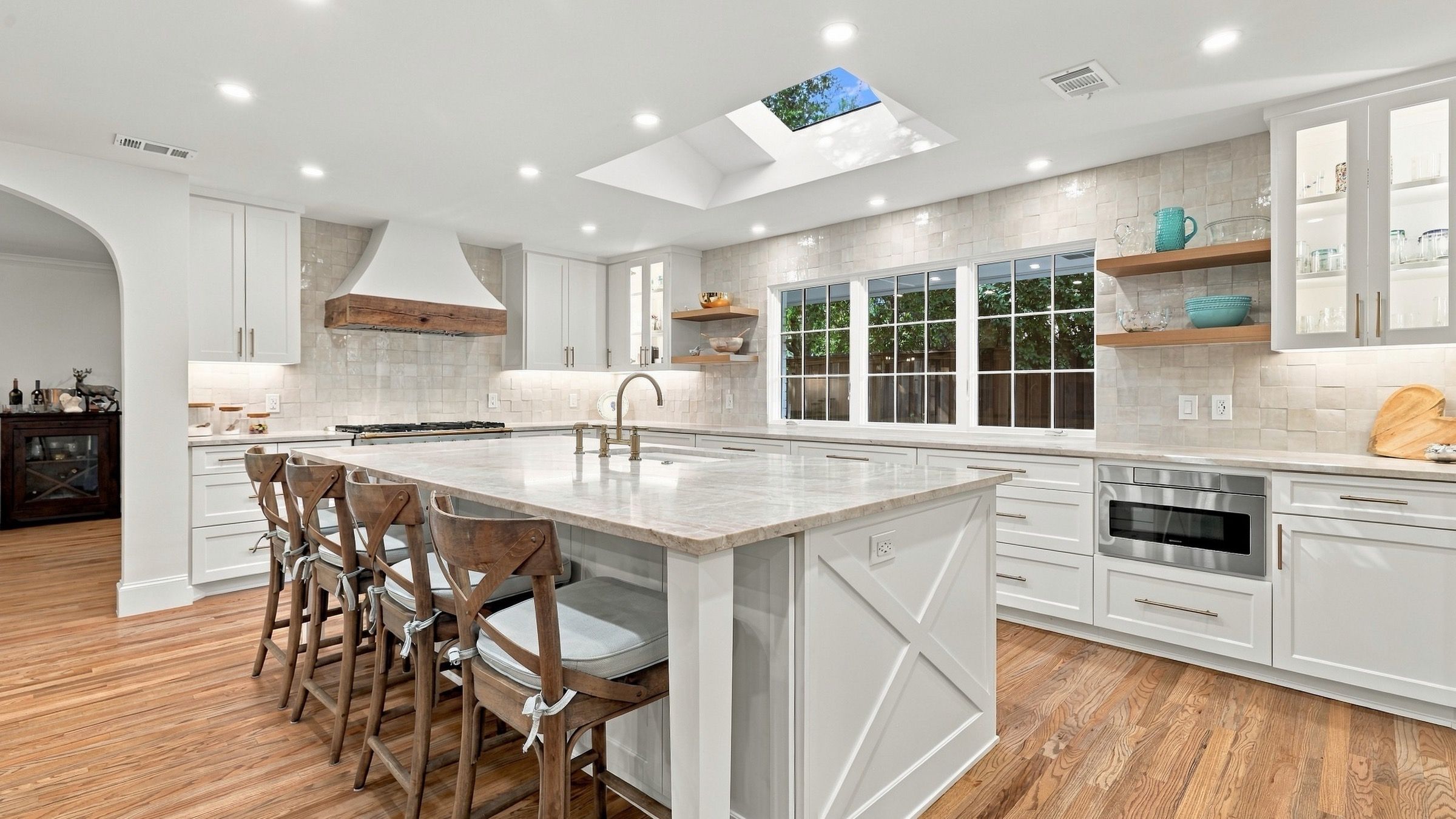 Kitchen after: a white island with wood stools, white cabinets and oak floors