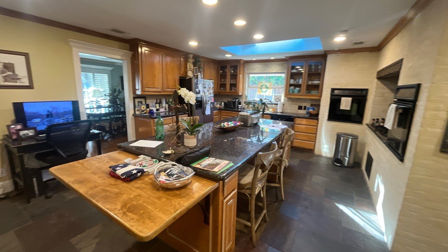 Kitchen before: wood cabinets, a dark tile floor and a two-level island