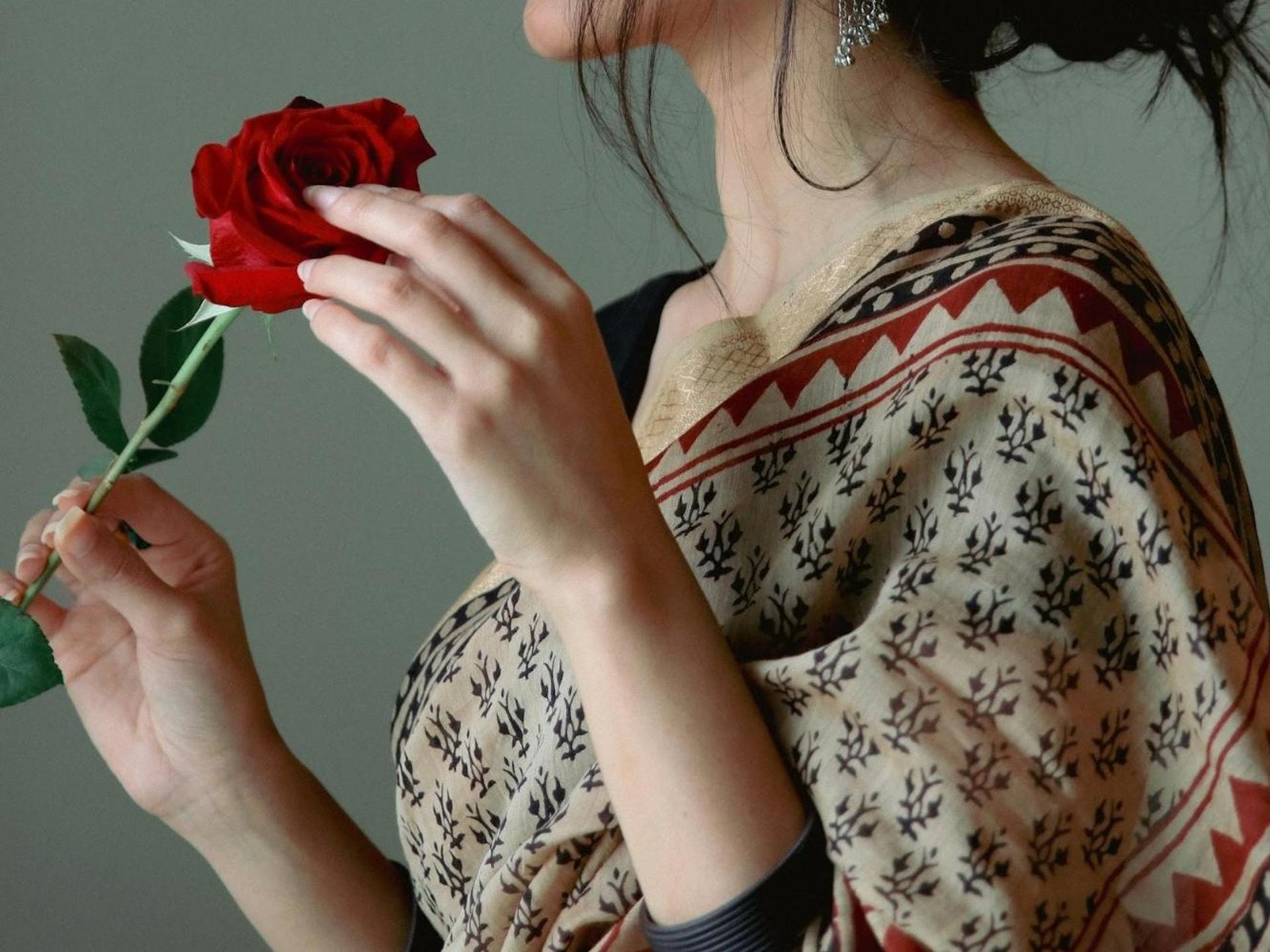 A woman wearing sari holding a rose
