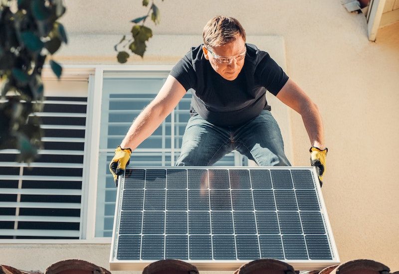 A person installing a solar panel on a roof