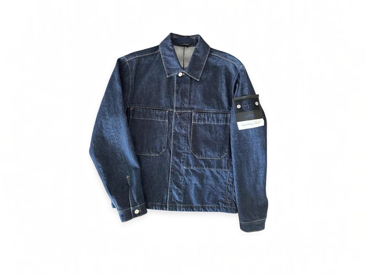 Een Stone Island Denim Research jas van indigo denim, plat gelegd op een witte achtergrond