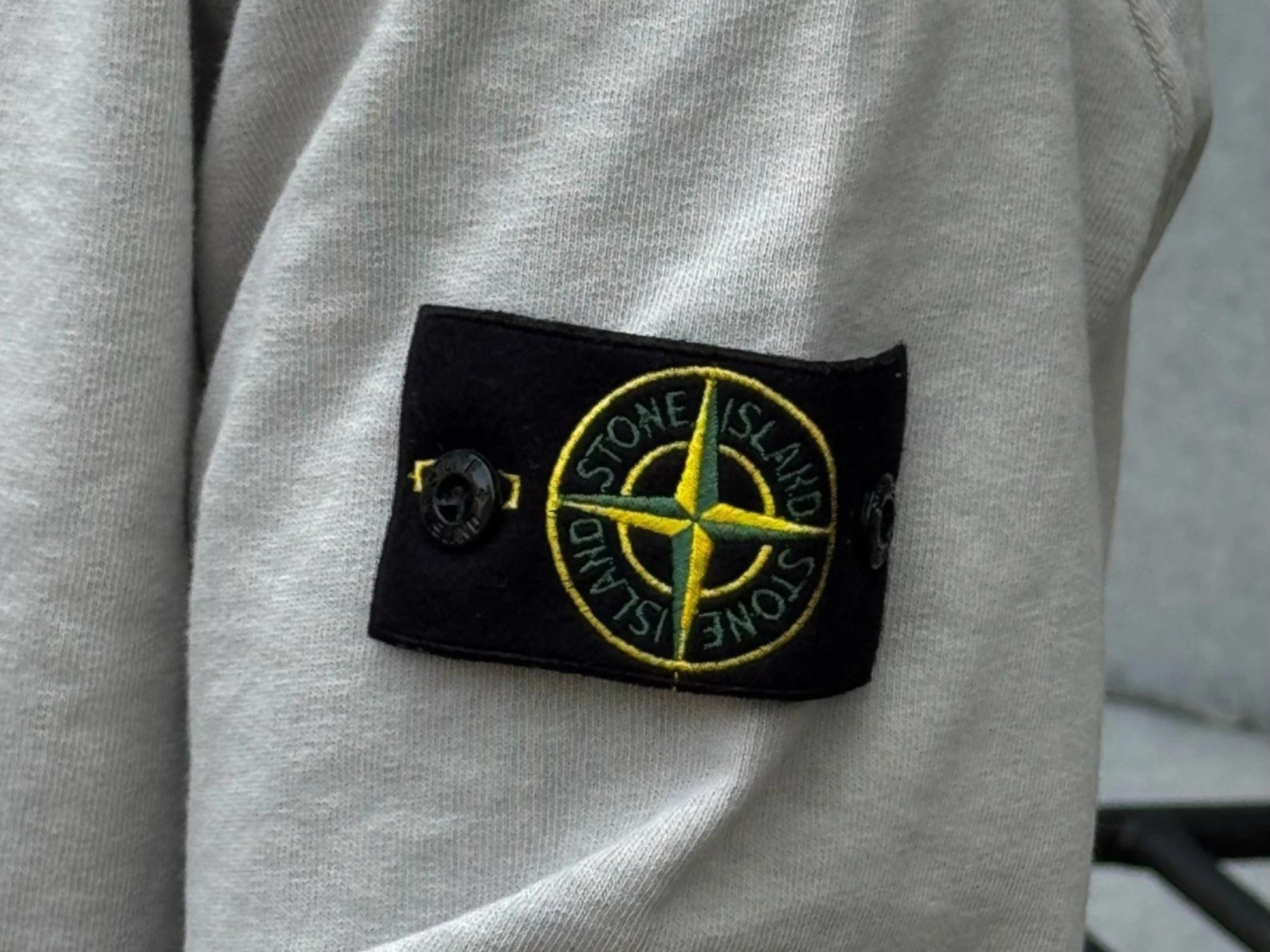 Iconic Stone Island compass badge on a grey sleeve of a sweater
