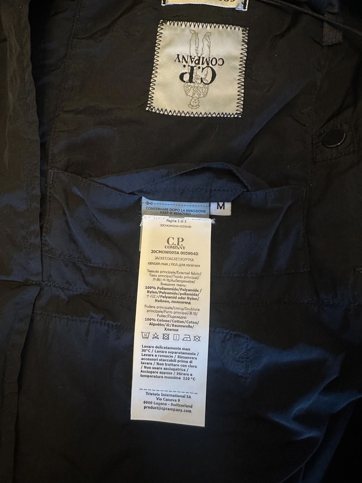 De labels in een C.P. Company jas: het geweven logolabel, een maatlabel met M en het wasetiket met de samenstelling