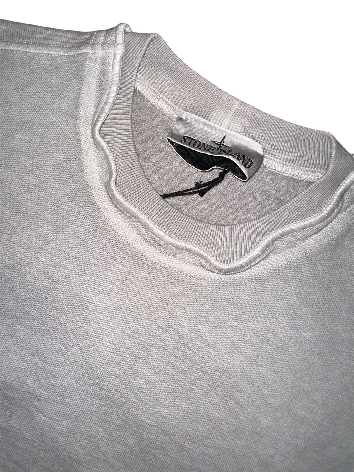 Close-up van de geribde kraag van een garment dyed Stone Island-sweater in grijs