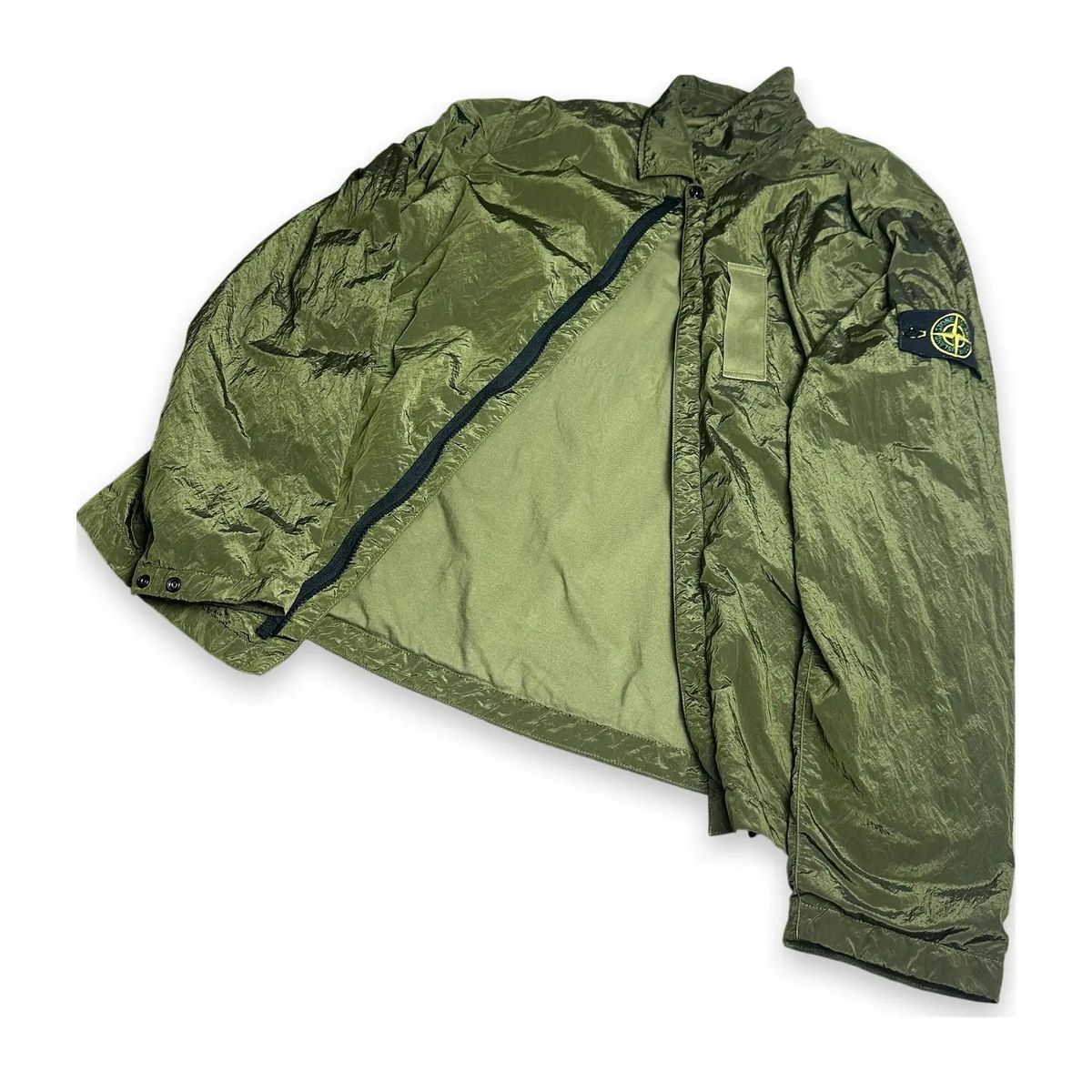 A Stone Island Nylon Metal overshirt in a shimmering olive finish, laid open to show the lining