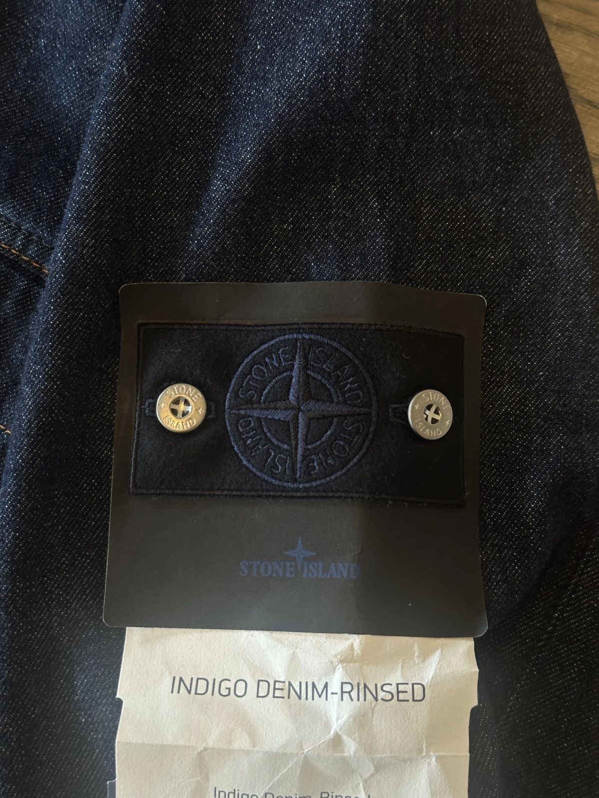 Close-up van de Denim Research badge van Stone Island: een donkerblauw kompas op donkerblauwe wol