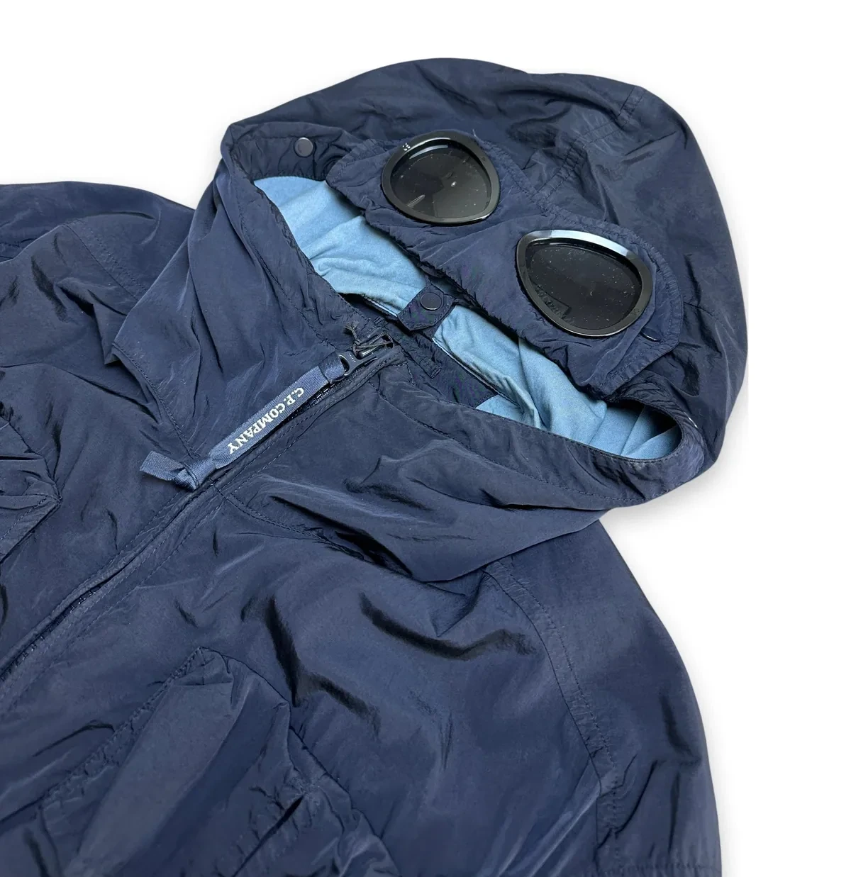 De capuchon van een marineblauwe C.P. Company Goggle Jacket met de twee ingebouwde lenzen