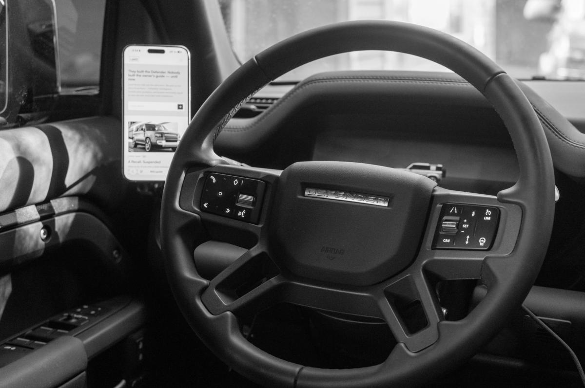 View from the driver's seat showing a phone mounted to the A-pillar grab handle, in line with the steering wheel