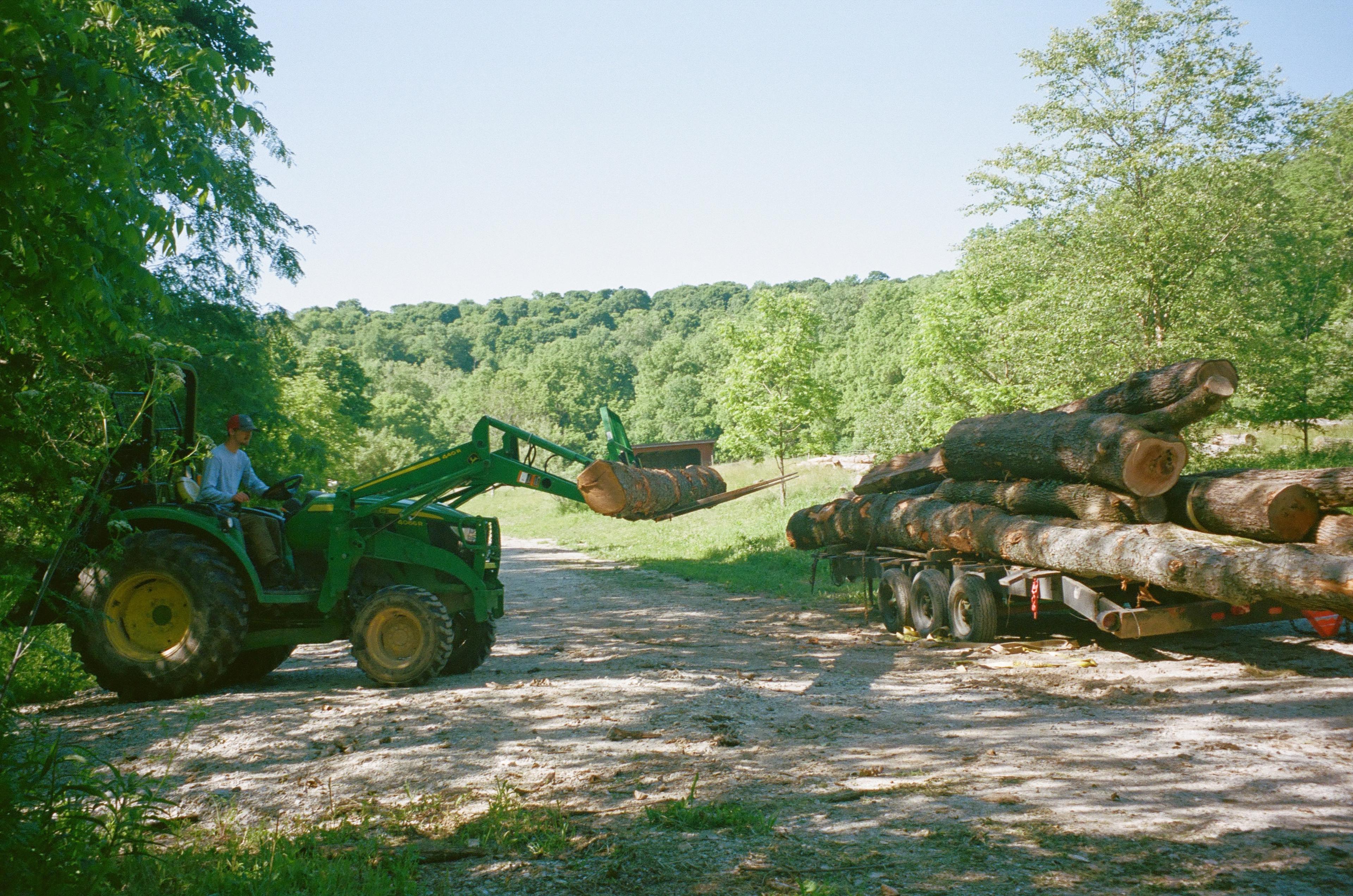 Paul uses a tractor to lift a log.