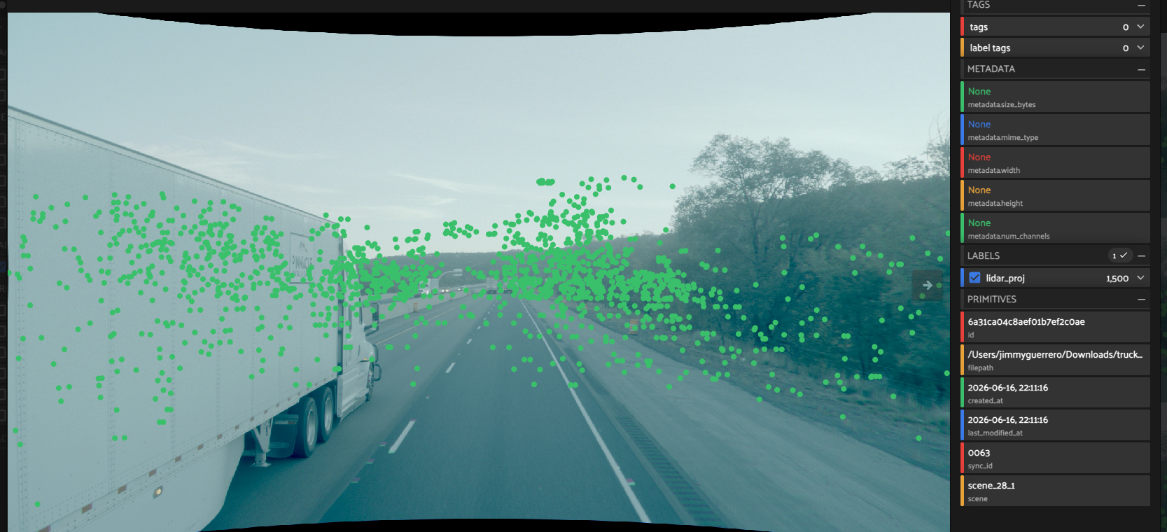 TruckDrive LiDAR points projected onto a highway camera image in FiftyOne, overlaying depth structure across the road, the truck ahead, and the tree line.