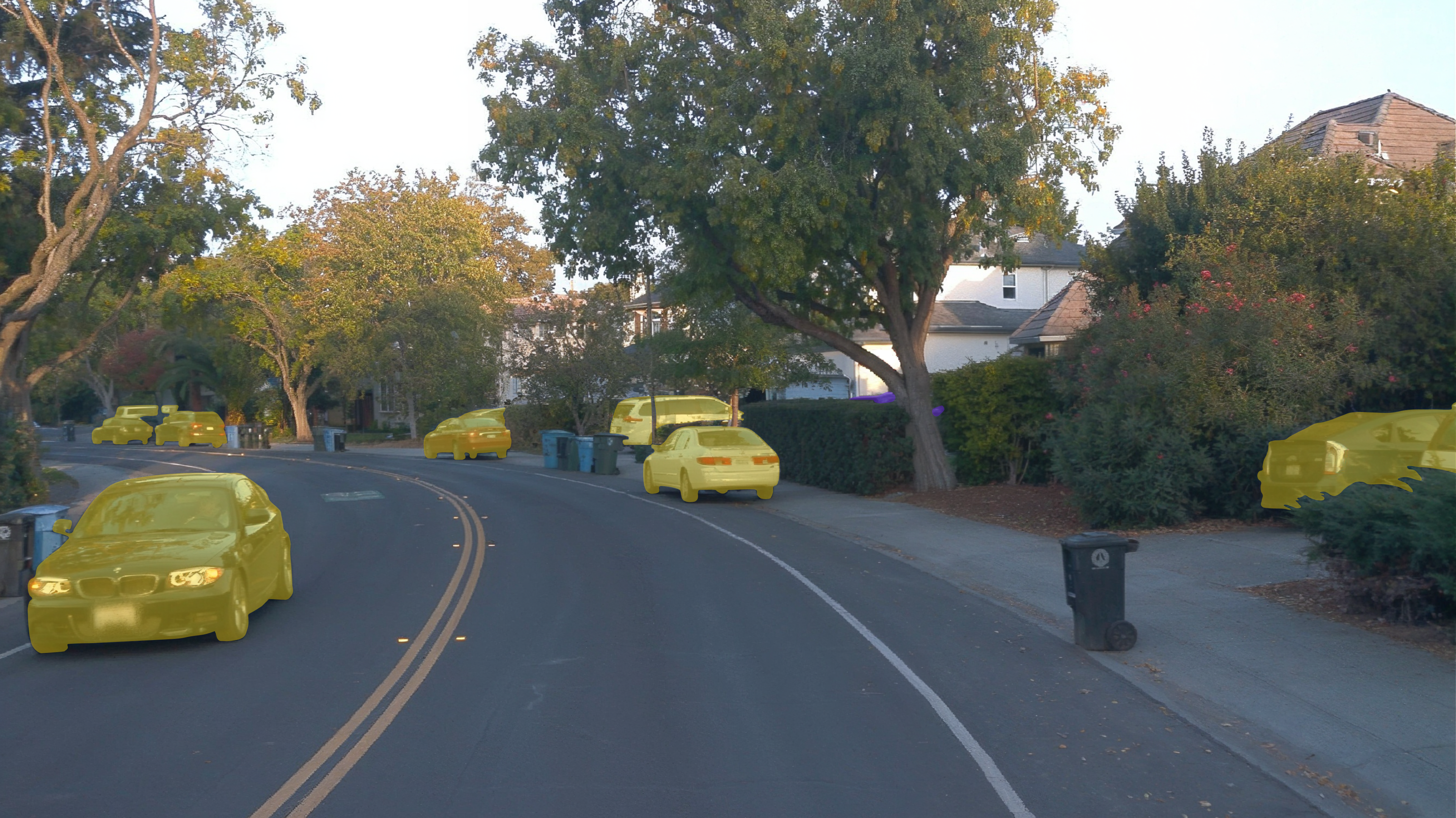 Suburban street scene with yellow semantic segmentation masks overlaid on parked and moving cars.