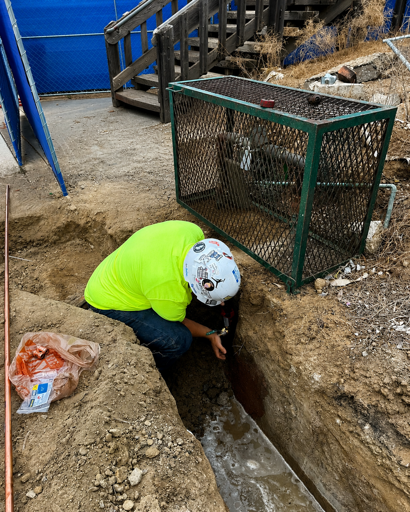 Plumber servicing commercial plumbing system in a restaurant kitchen