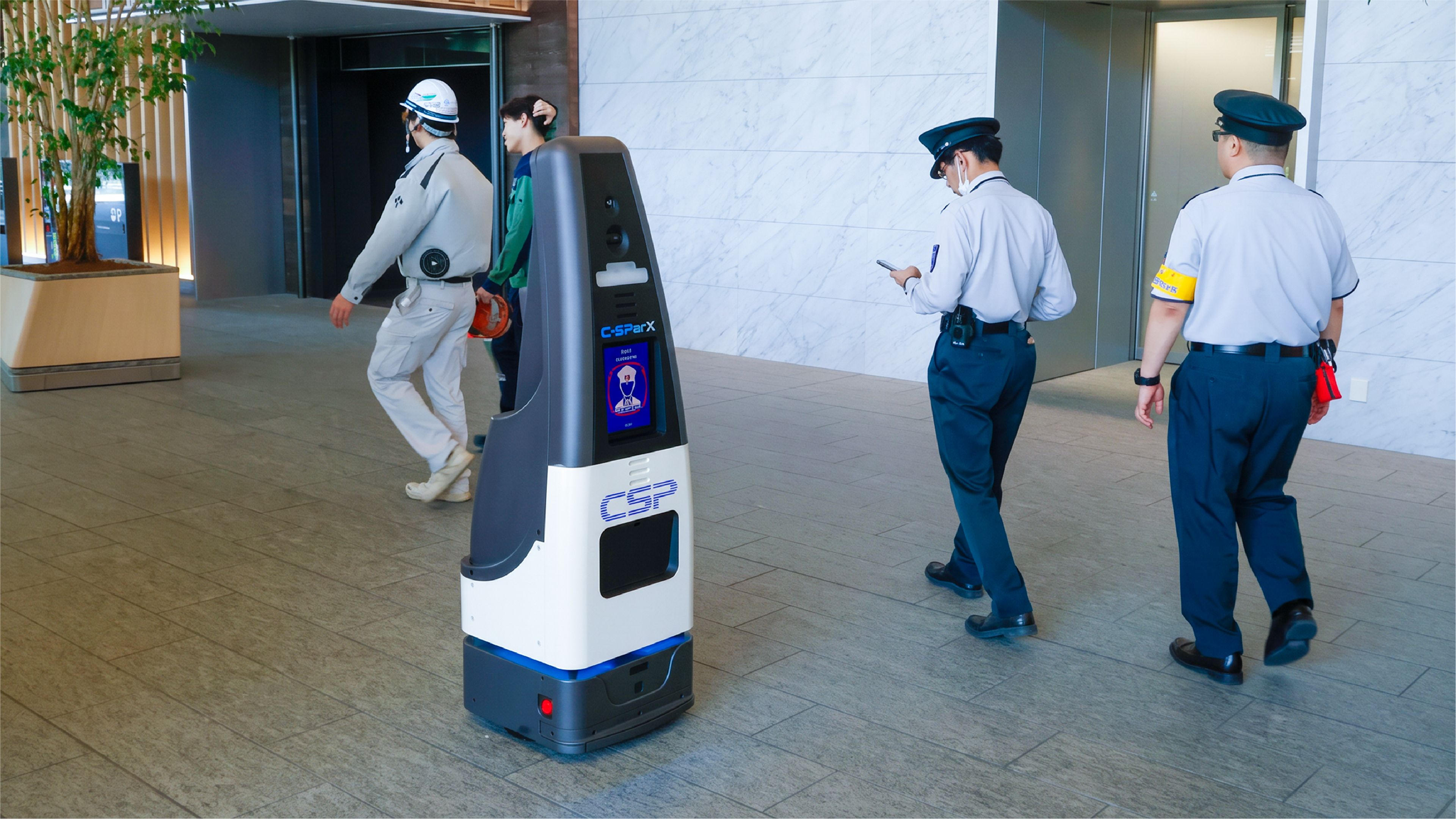 CSP-branded security patrol robot with a display screen moving through an office lobby as two uniformed guards and a worker pass by