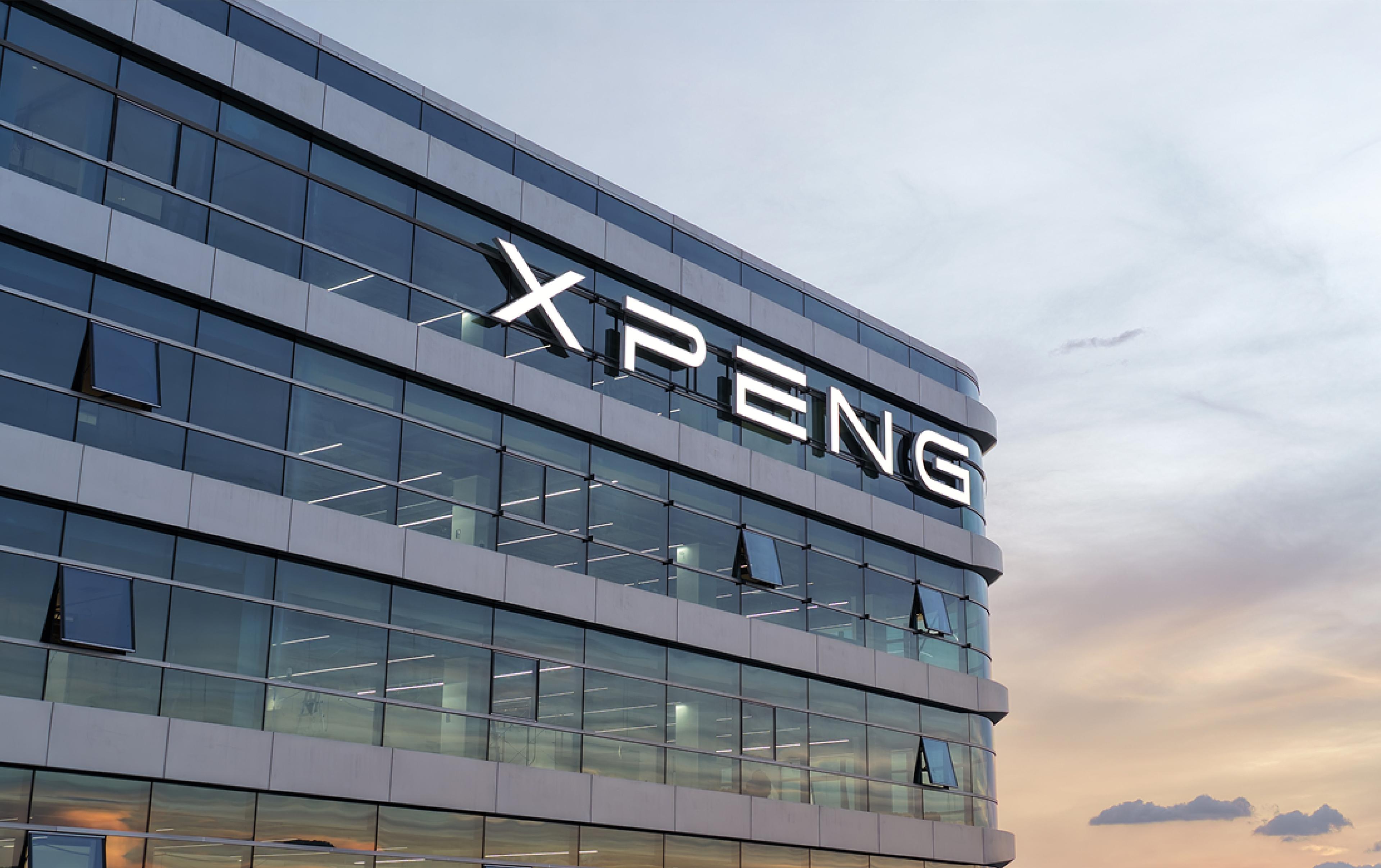 The XPeng logo illuminated on the glass facade of a corporate building at dusk, with a pastel sky in the background.