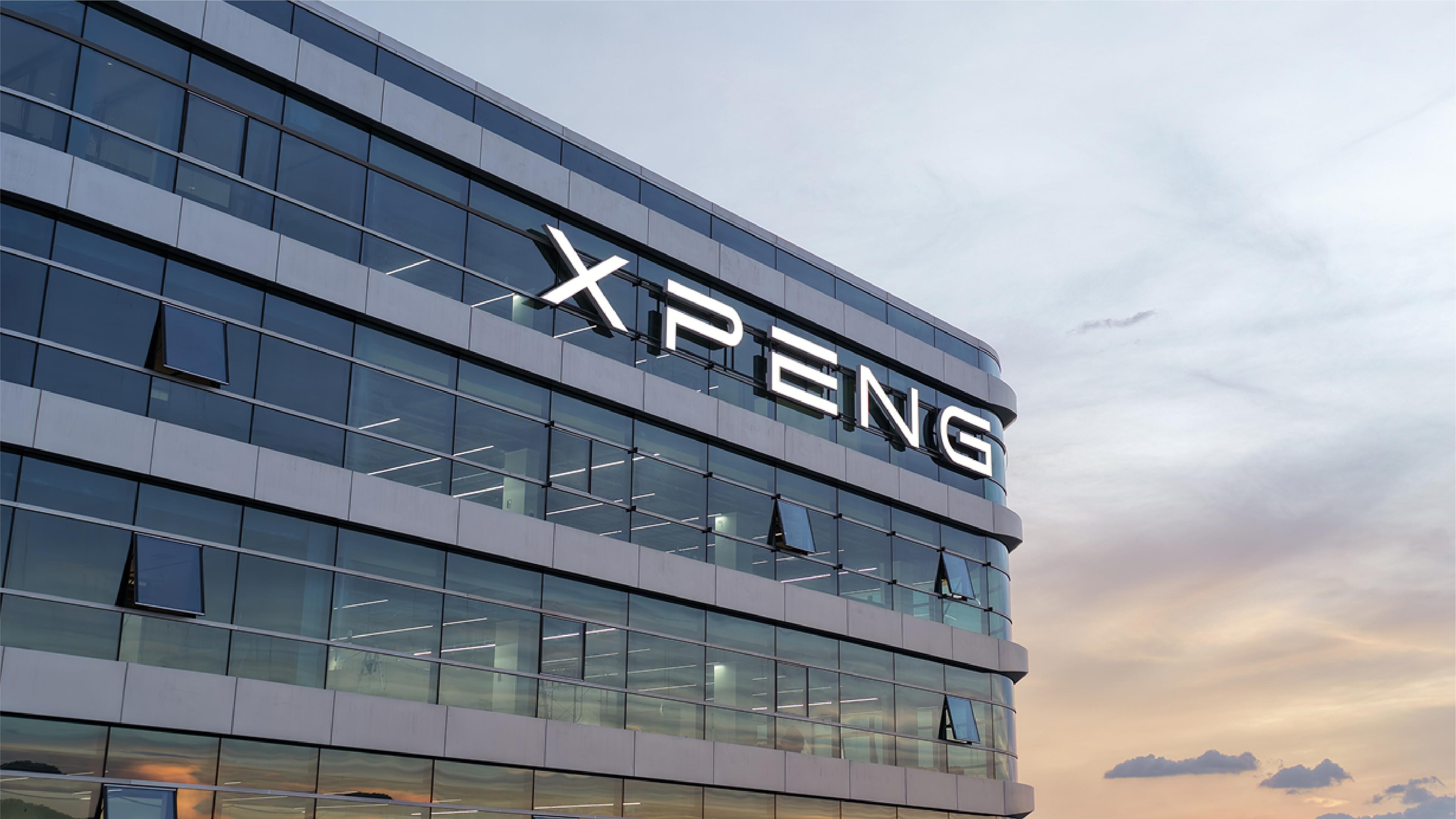 The XPeng logo illuminated on the glass facade of a corporate building at dusk, with a pastel sky in the background.