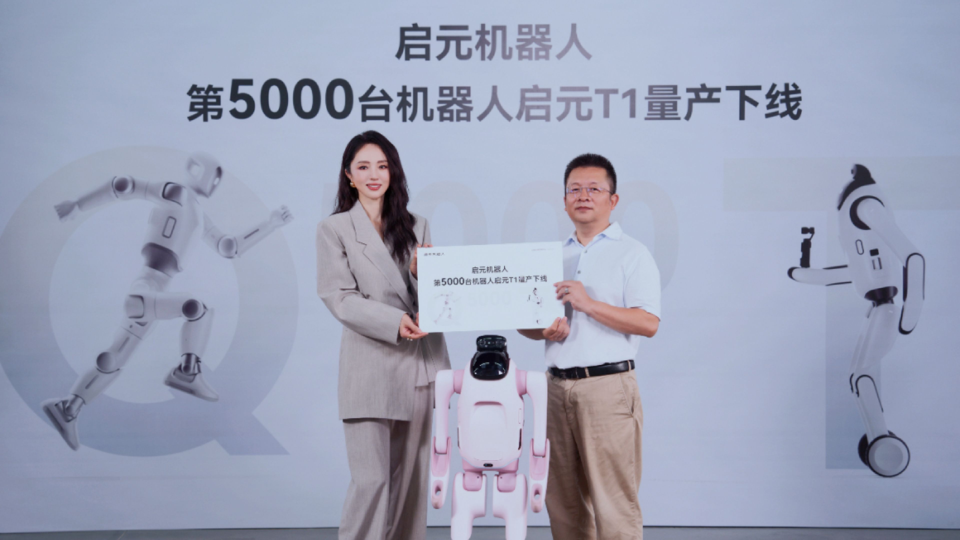 Two people pose with a pink Qiyuan T1 robot and a commemorative certificate marking the 5,000th robot's production.