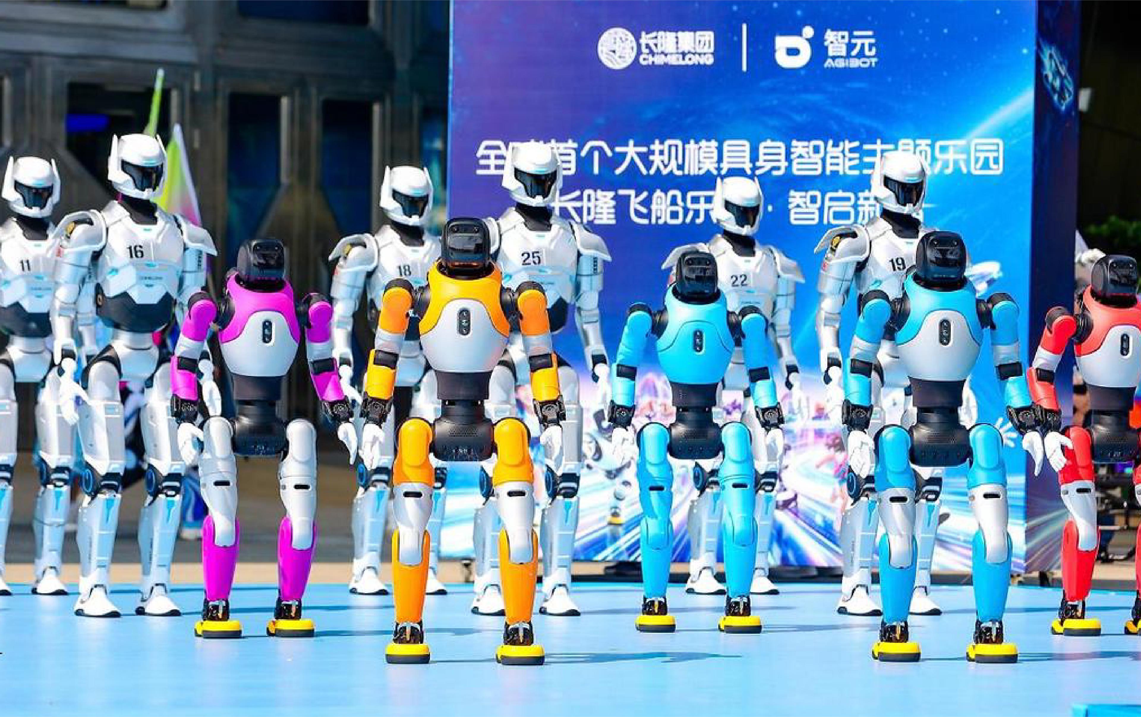A group of colorful humanoid robots stands on a stage during a public technology event, with a large Chinese-language display screen in the background.