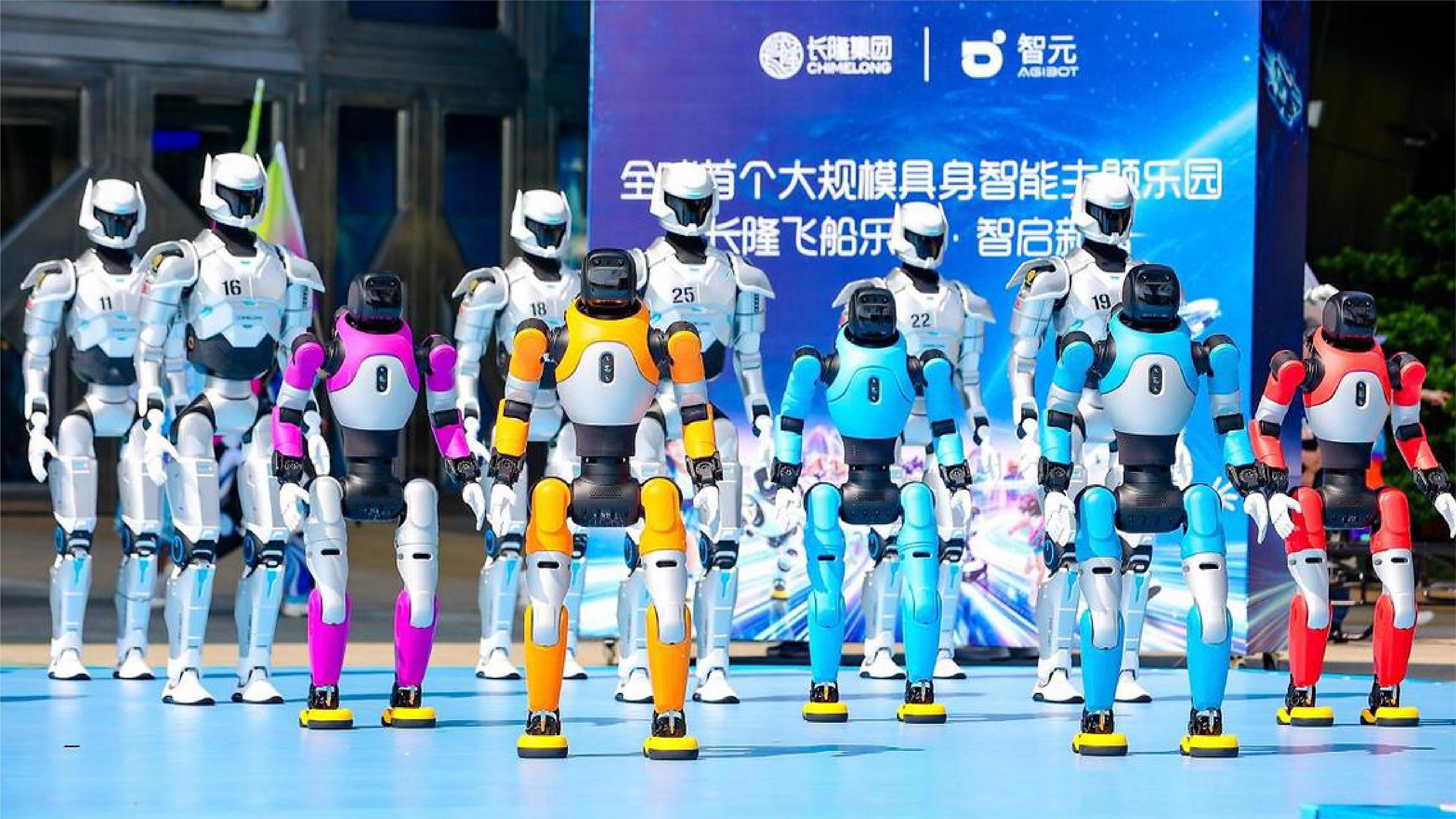 A group of colorful humanoid robots stands on a stage during a public technology event, with a large Chinese-language display screen in the background.