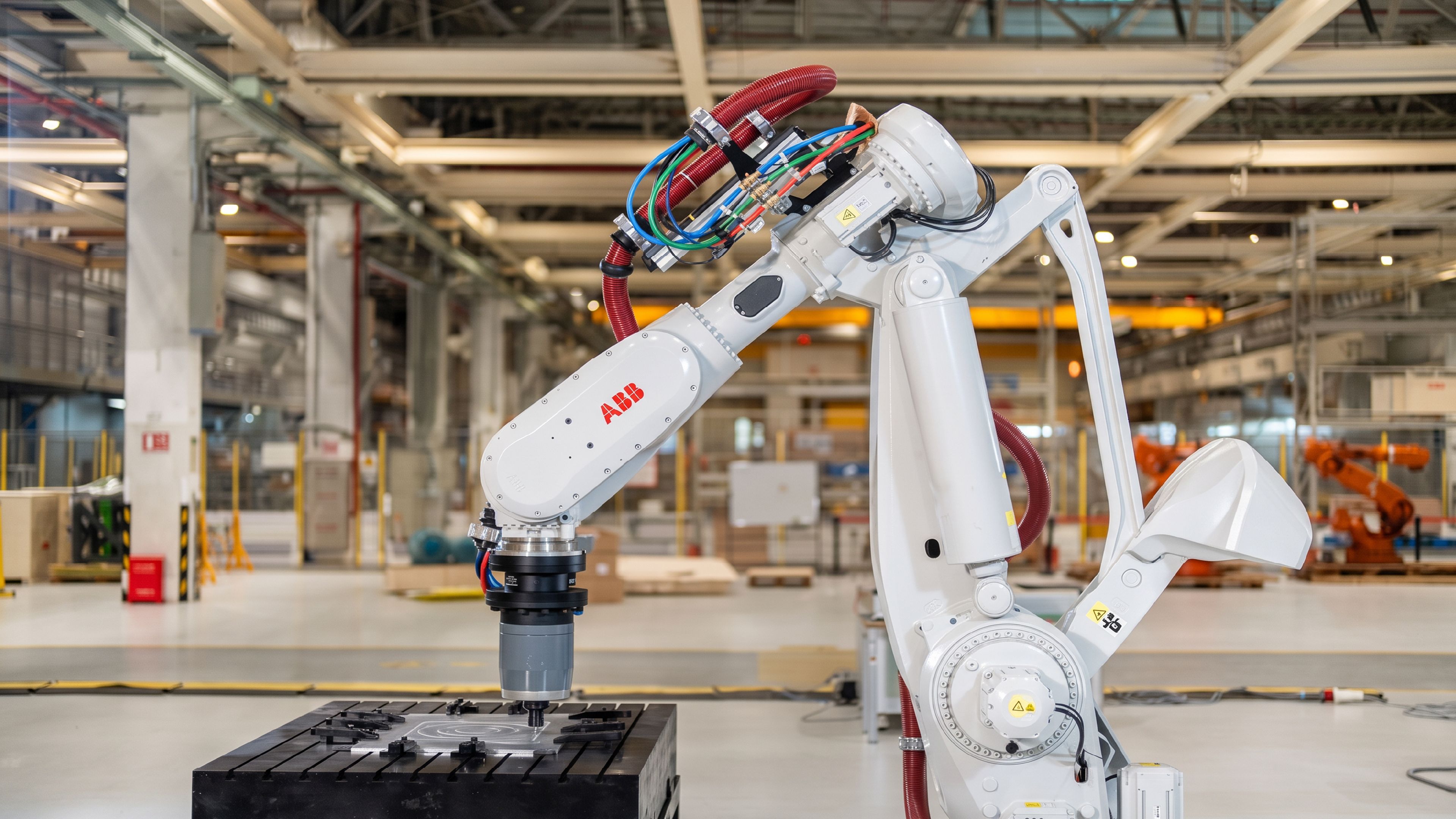 An ABB industrial robot arm machining a part on a factory floor