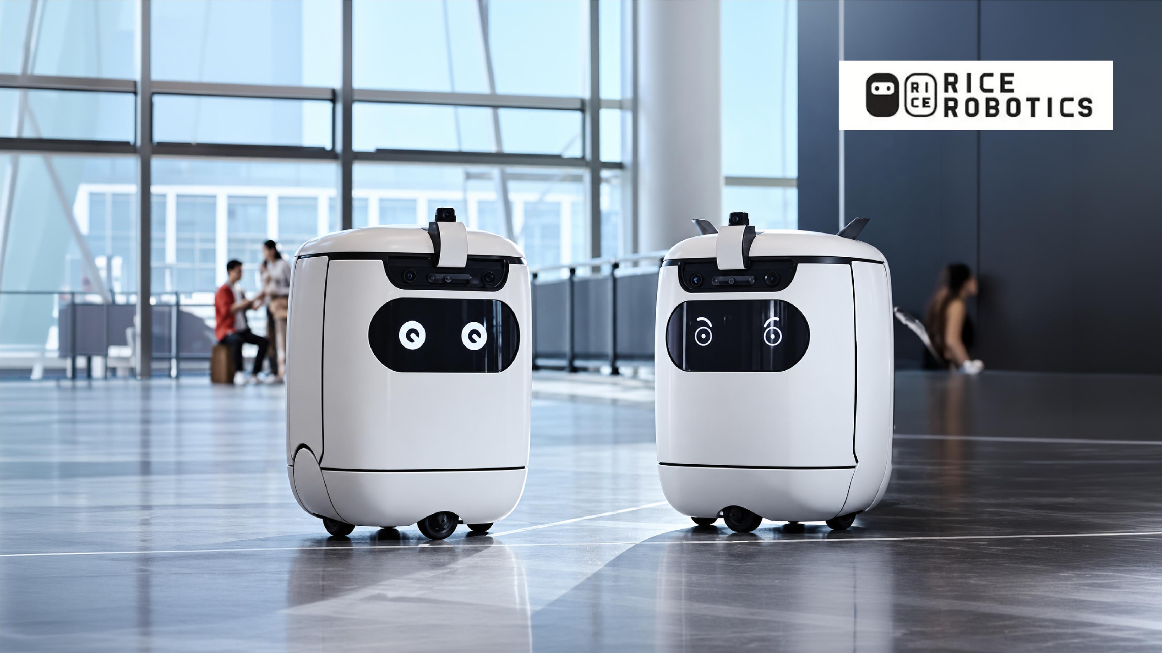 Two Rice Robotics service robots with digital facial expressions, front-mounted cameras and wheeled bases.