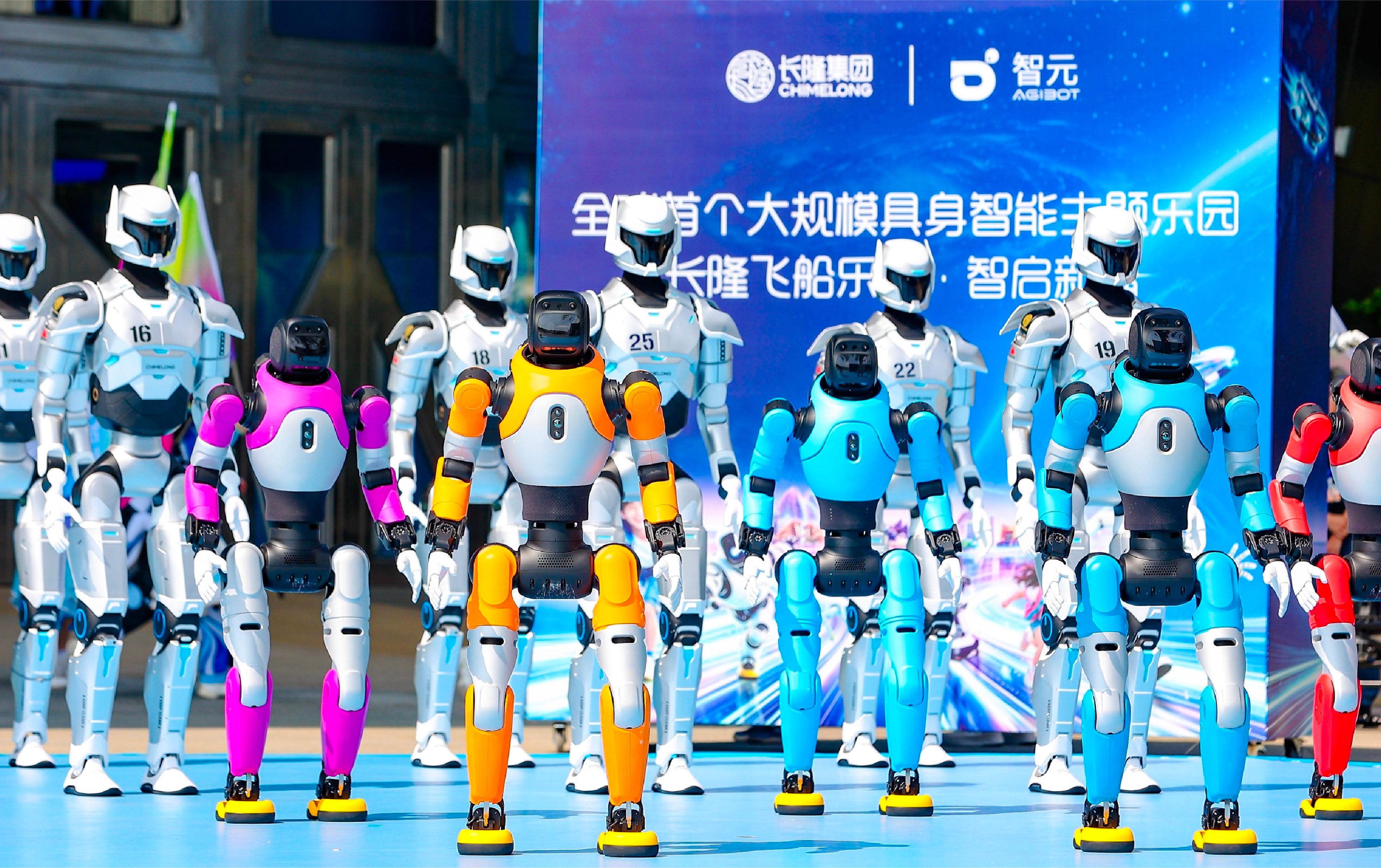 AGIBOT humanoid robots in colorful and white designs stand together during an event at Chimelong Spaceship Park in Zhuhai, China.