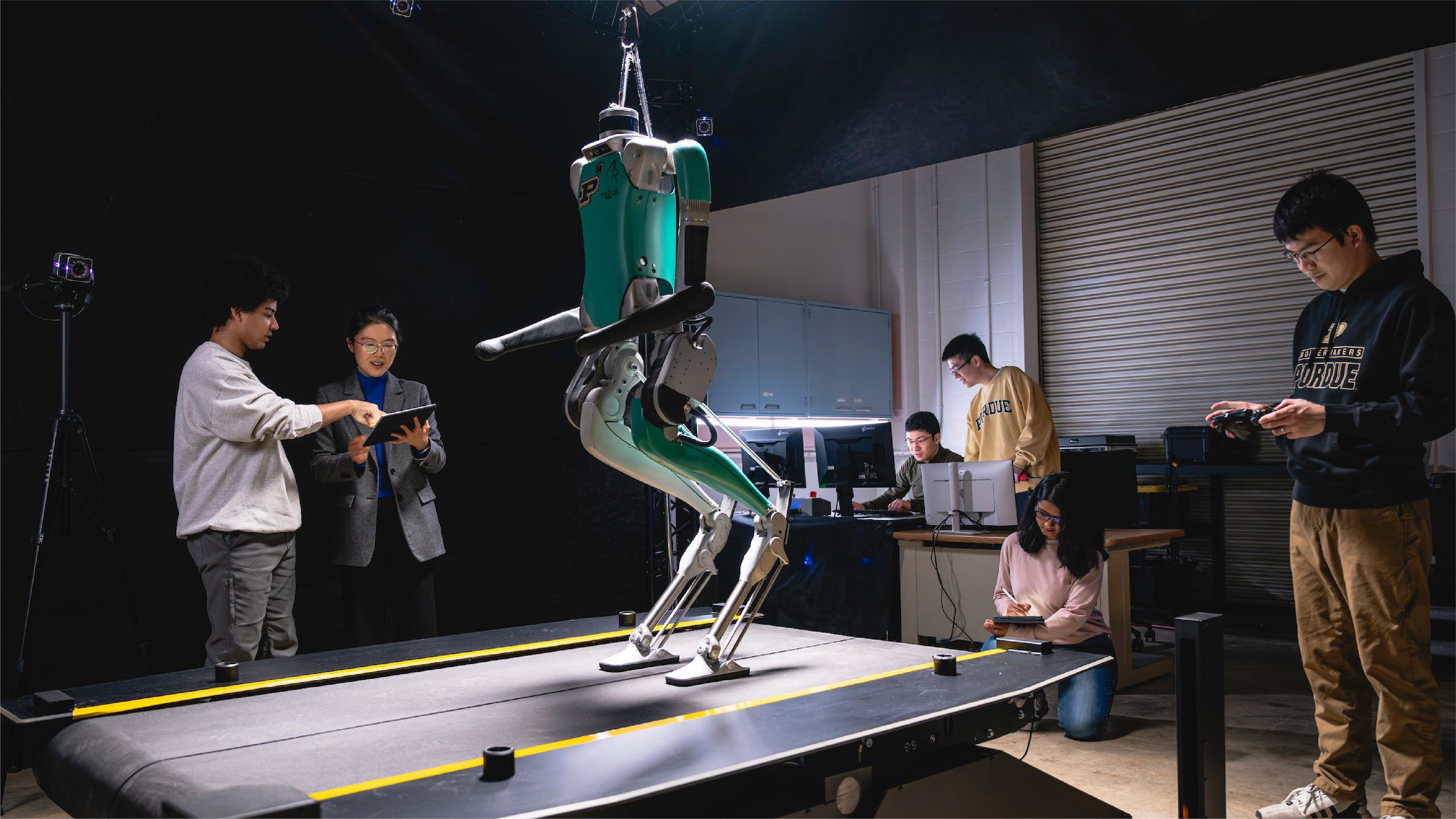 Researchers test a bipedal robot on a treadmill in a university robotics laboratory.
