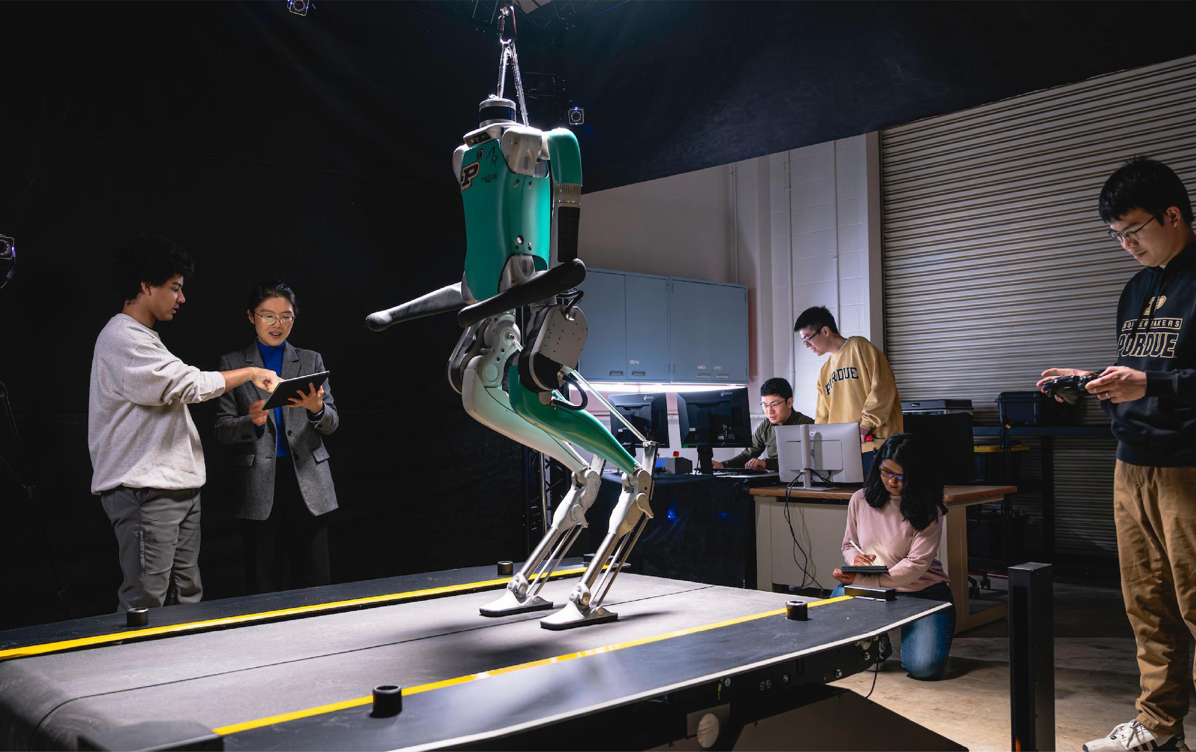 Researchers test a bipedal robot on a treadmill in a university robotics laboratory.