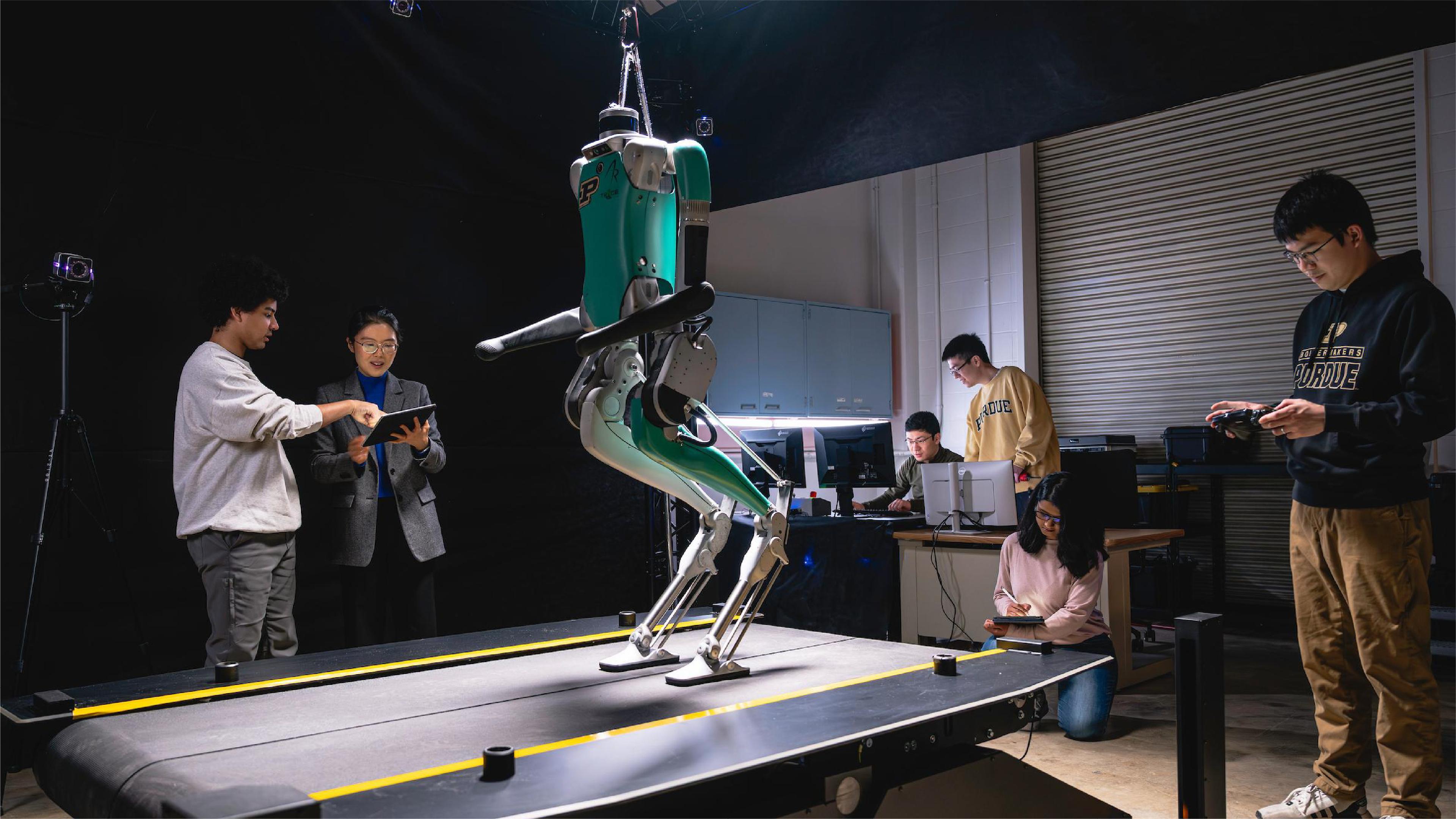 Researchers test a bipedal robot on a treadmill in a university robotics laboratory.